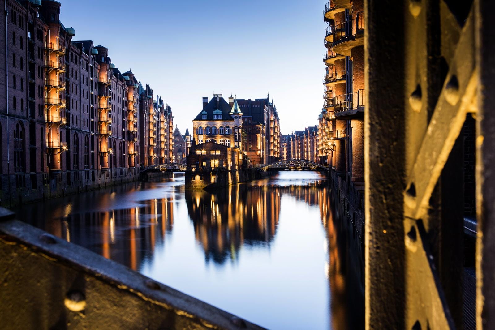 Beleuchtete Speicherstadt Hamburg, Deutschland mit reflektierendem Wasser bei Dämmerung.