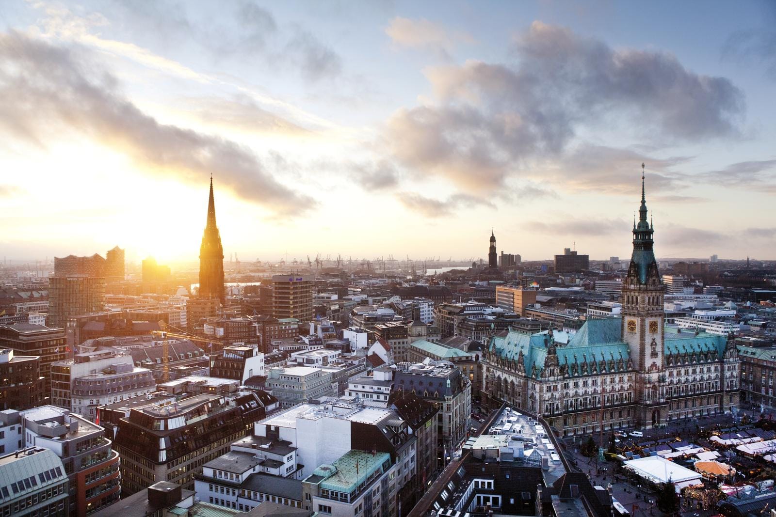 Hamburg Skyline bei Sonnenuntergang mit Rathaus und Elbphilharmonie im Hintergrund.