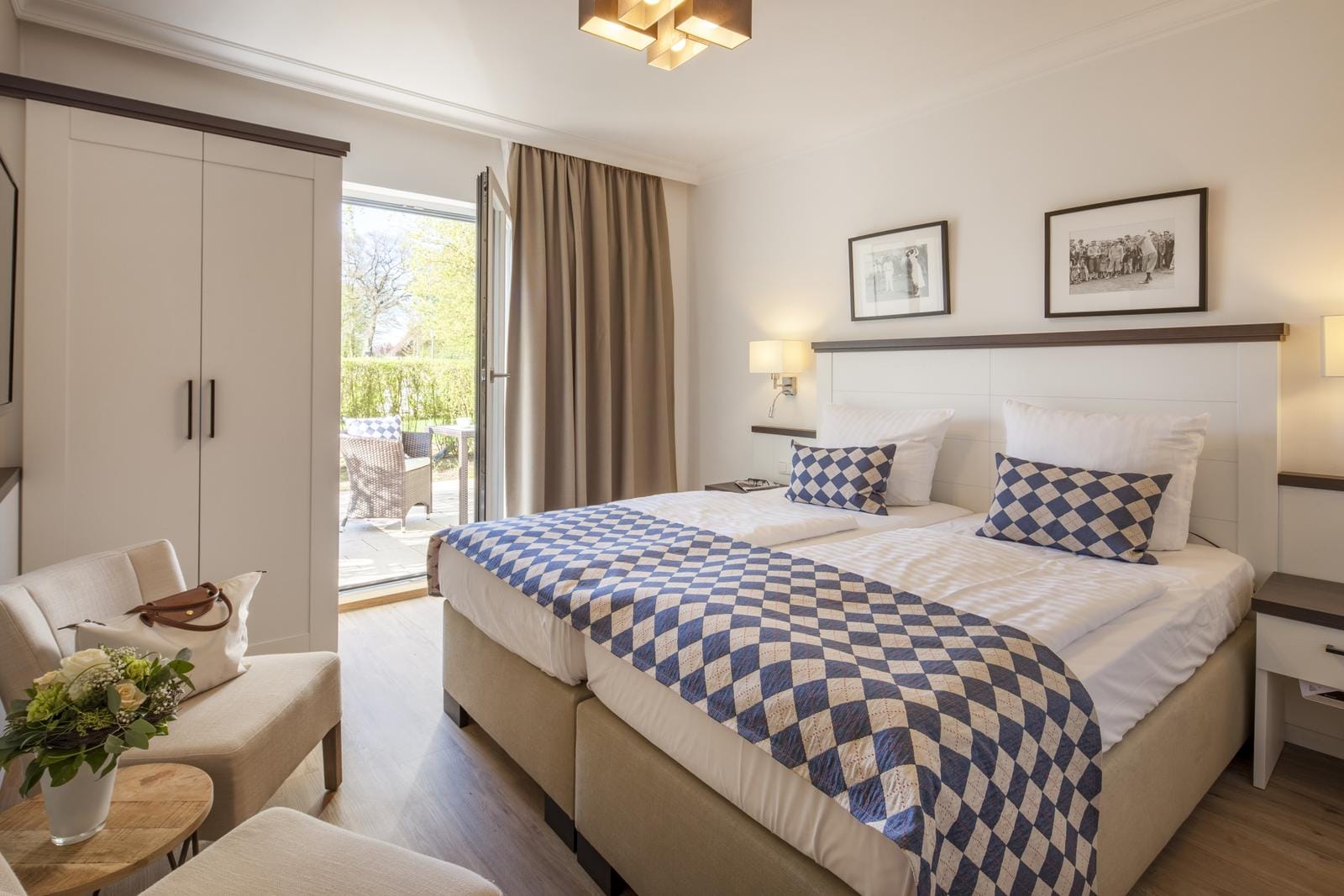 Helles Hotelzimmer mit Doppelbett, blauen Karomustern und Zugang zur Terrasse.
