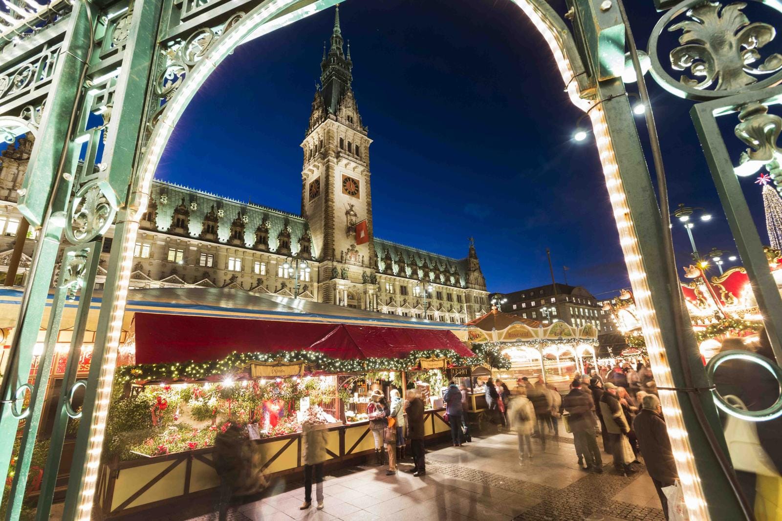 Weihnachtsmarkt am Hamburger Rathaus bei Nacht, festlich beleuchtet vor klarem Himmel.
