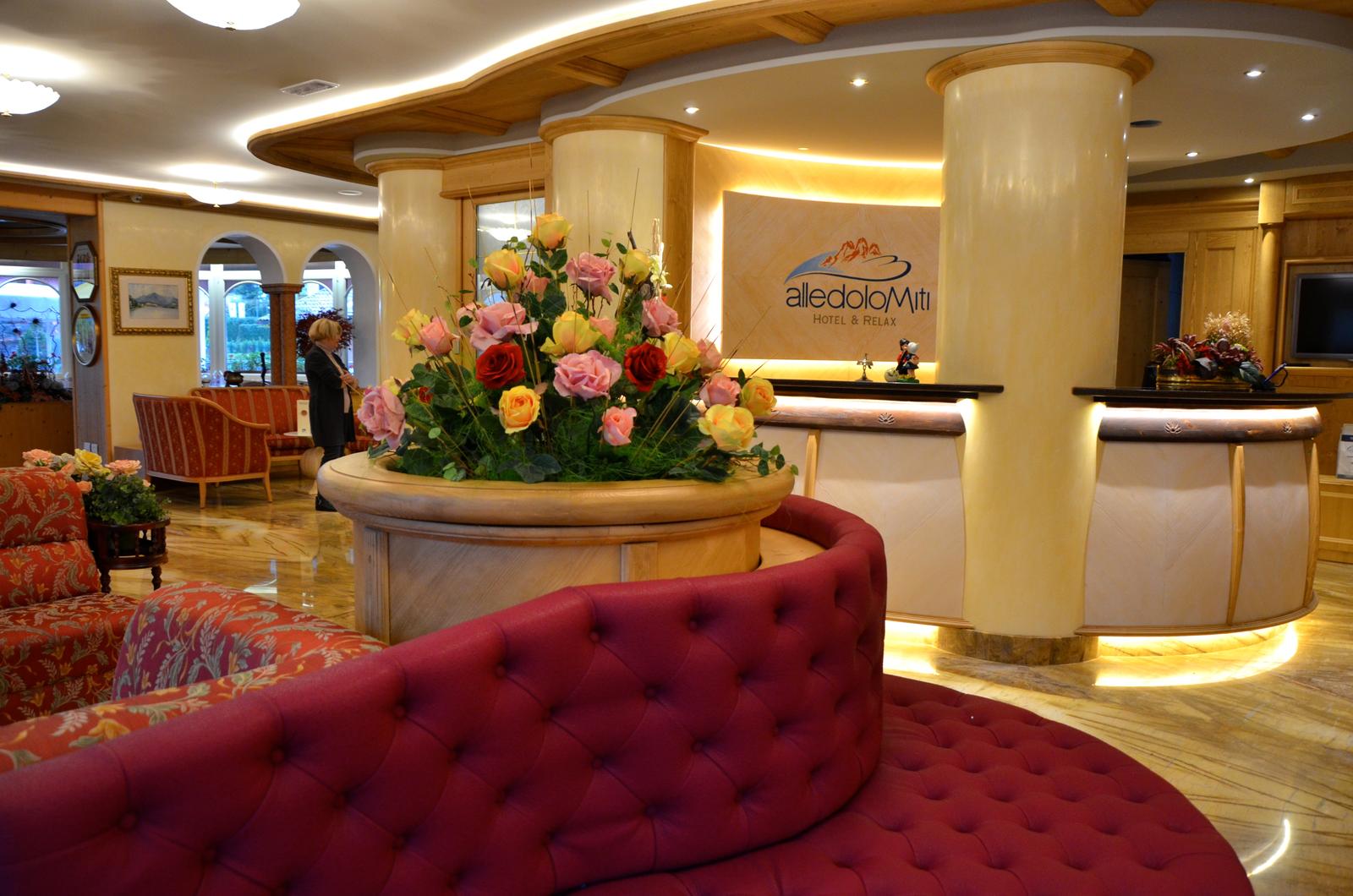 Elegante Hotellobby mit roten Polstermöbeln, Blumenarrangement und warmer Beleuchtung.