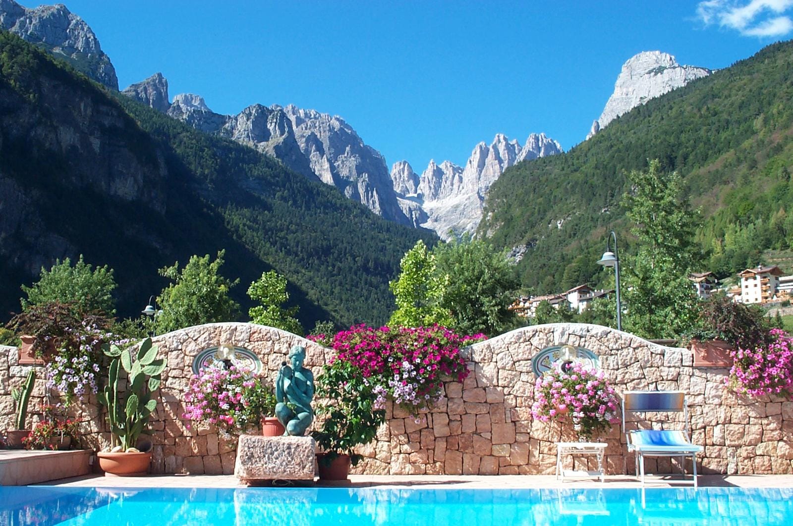 Bergkulisse mit Pool, Steinmauer und Blumen in einem italienischen Dorf.