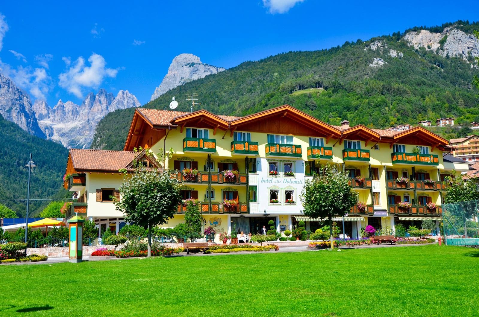 Gemütliches Berghotel in den Alpen, mit Balkon, blühenden Blumen und grünen Wiesen.