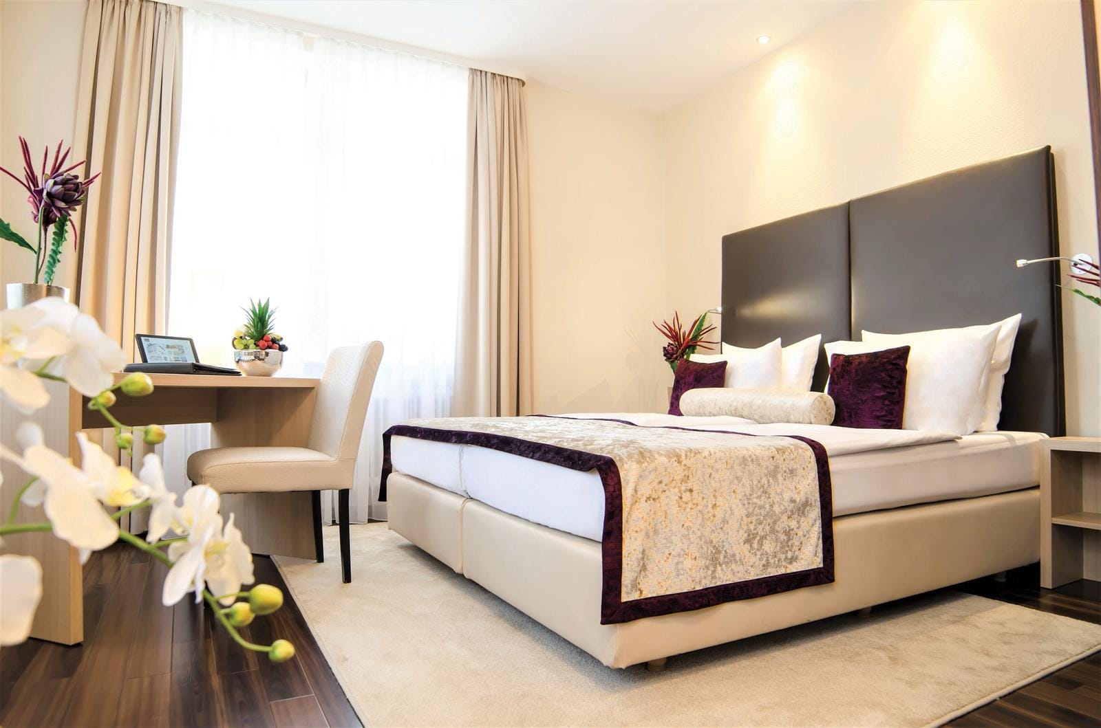 Modernes Hotelzimmer mit Doppelbett, warmen Farben und eleganten Dekorationen.