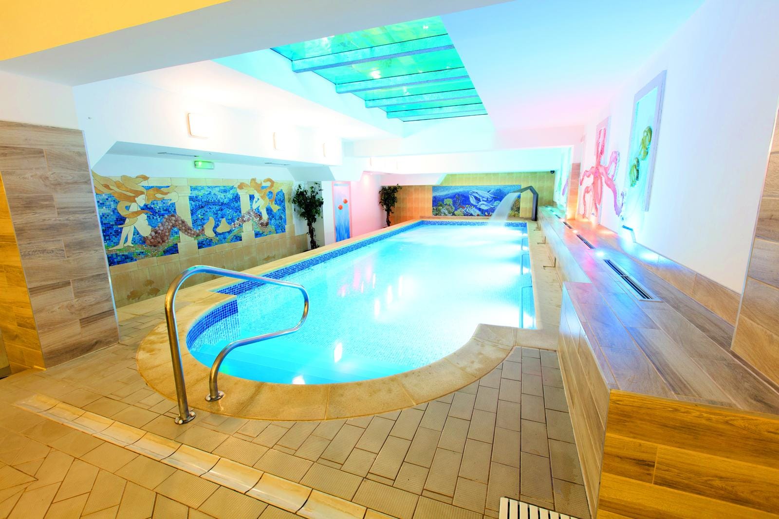 Helles Hotel-Spa mit modernem Pool, Mosaiken und buntem Licht.