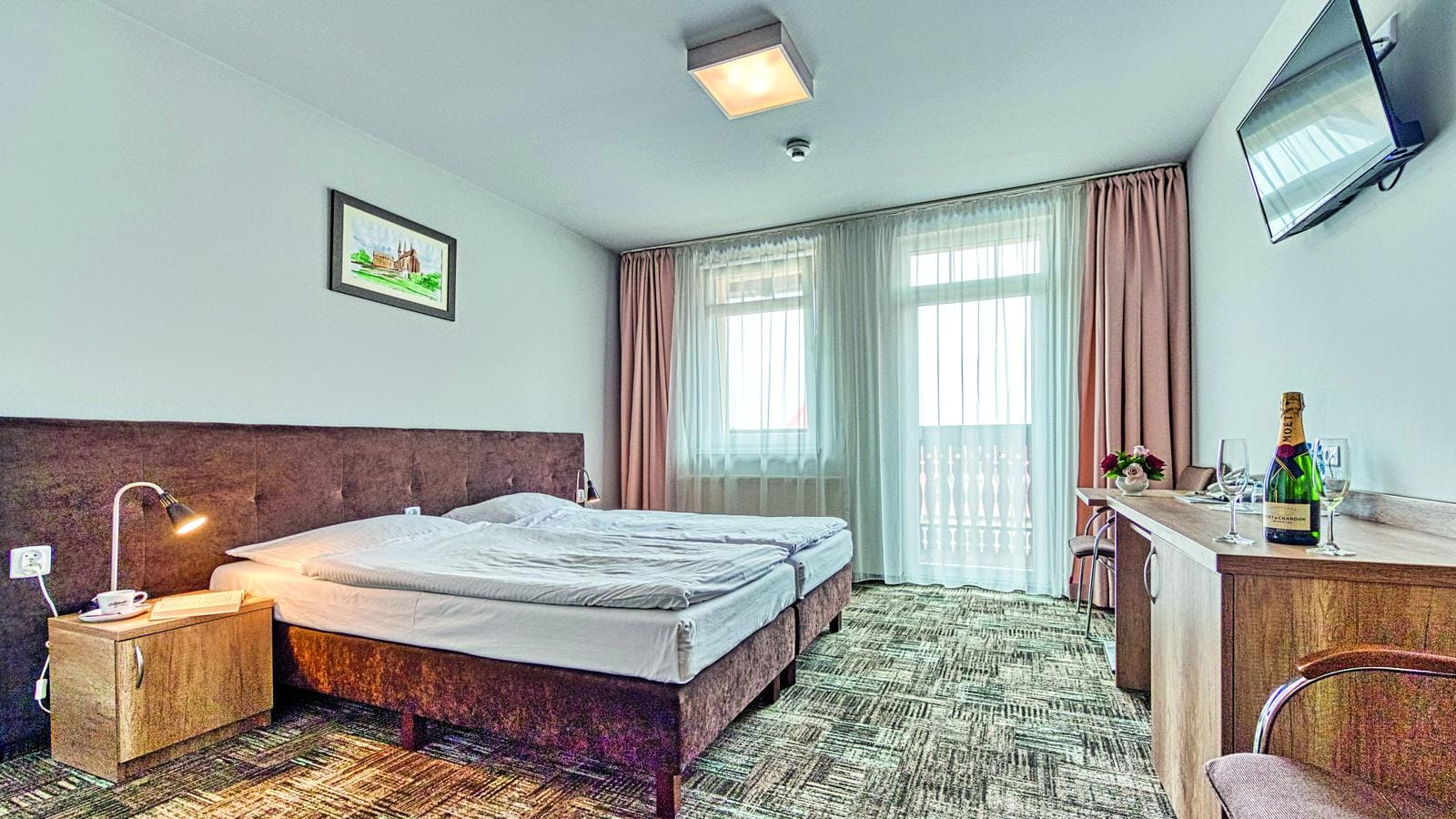 Helles Hotelzimmer mit Kingsize-Bett, modernem Stil, pastellfarbene Vorhänge.