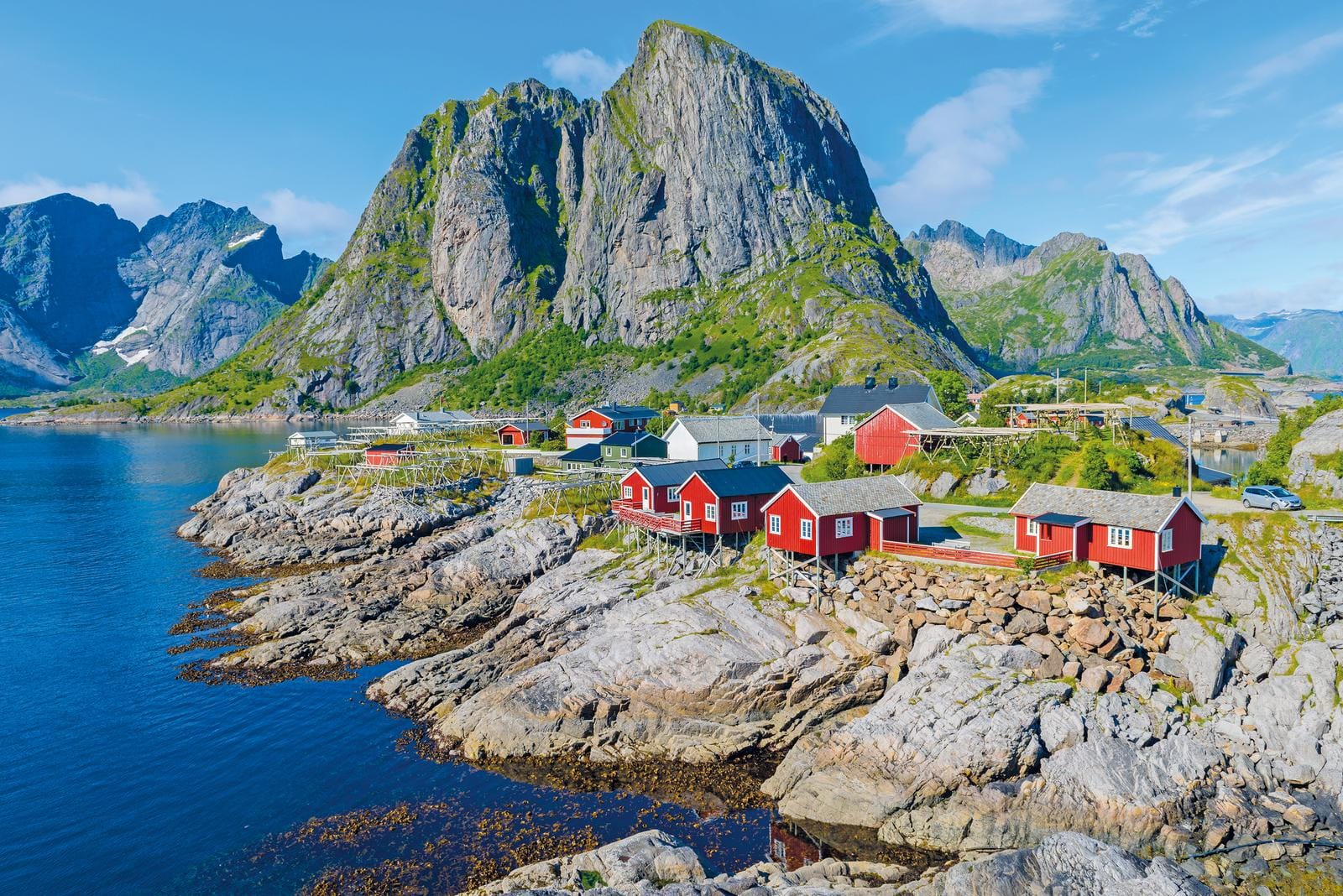 Rote Fischerhütten vor steilen Bergen an der Küste Norwegens im Sommer.