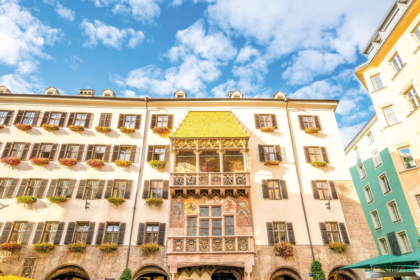 Historisches Gebäude in Innsbruck mit goldenem Dach, blauer Himmel, Blumen an Fenstern.