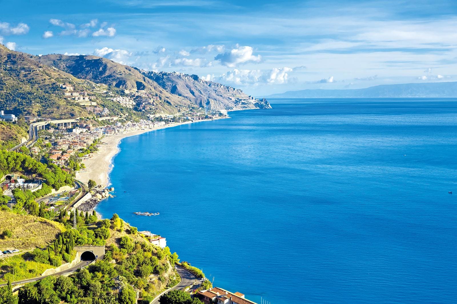 Mittelmeer-Küstenlandschaft Siziliens mit Bergen und blauem Himmel.