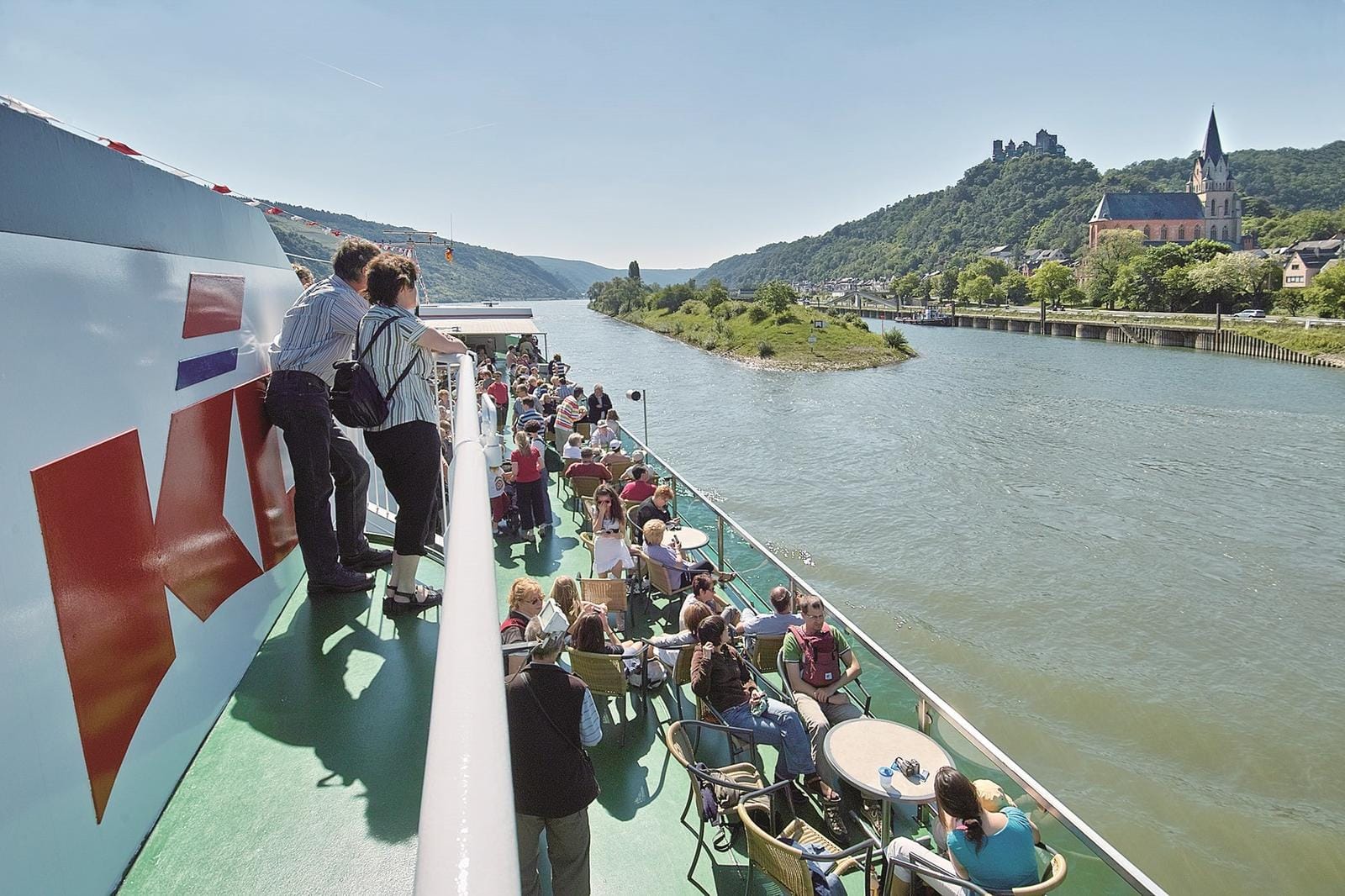 Passagierschiff auf dem Rhein mit Burg und Kirche am Ufer, sonnige Aussicht.