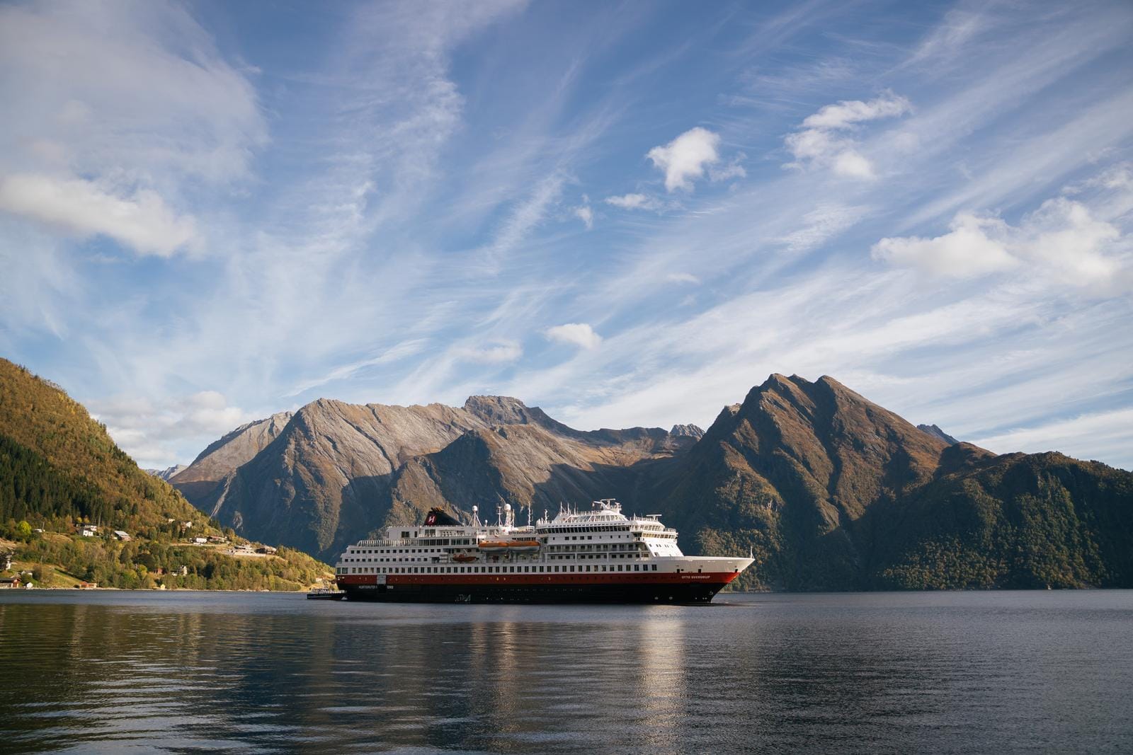 Kreuzfahrtschiff gleitet durch Norwegens Fjorde, umgeben von majestätischen Bergen.