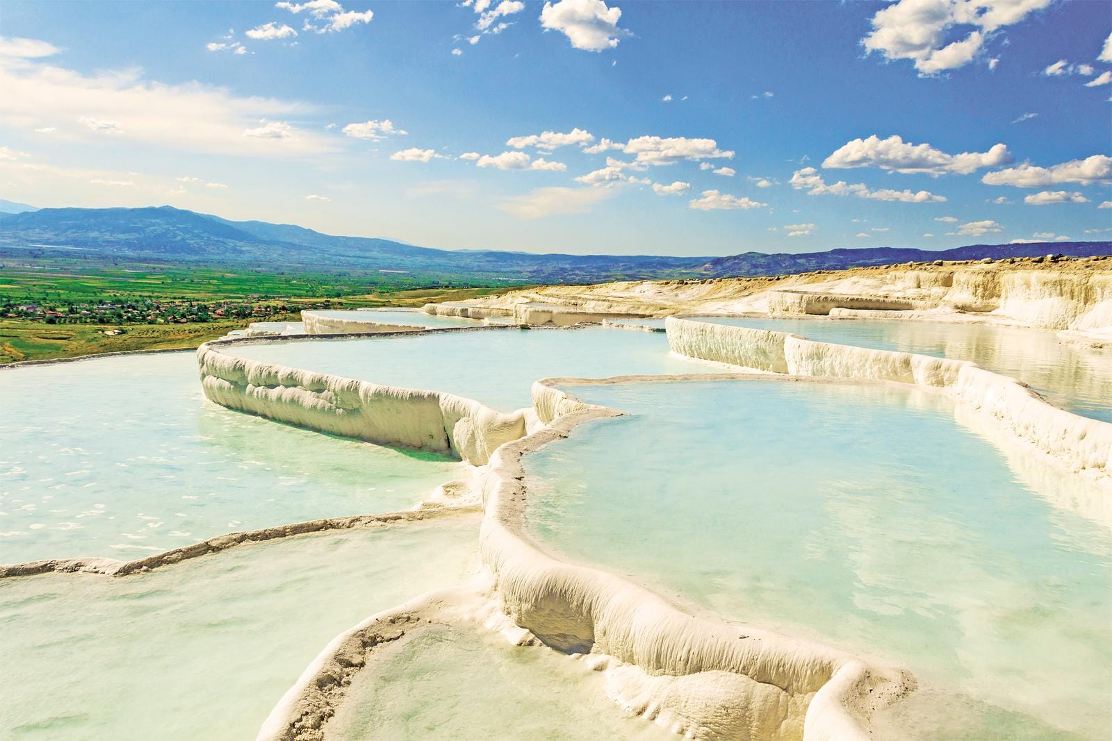 Natürliche Terrassen von Pamukkale, Türkei, mit türkisfarbenem Wasser und blauem Himmel.