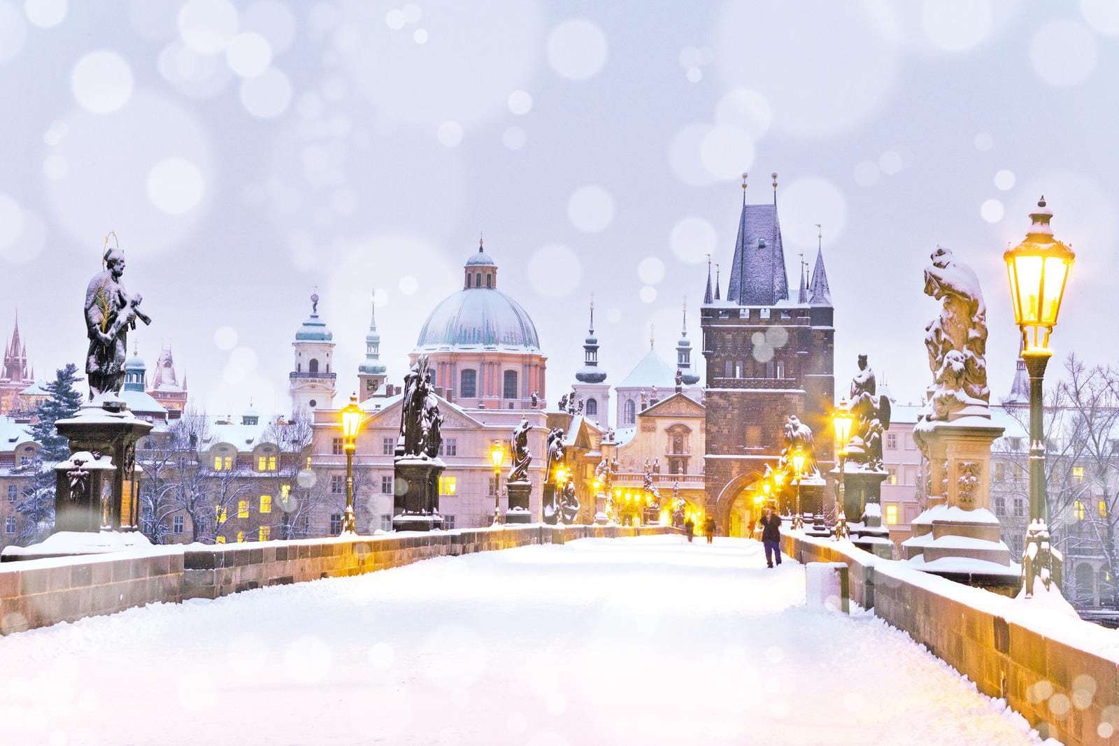 Verschneite Karlsbrücke in Prag, Tschechien, mit erleuchteten Laternen und Statuen.