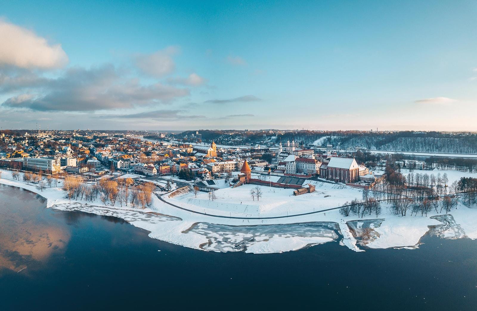 Winterliche Stadtlandschaft von Kaunas, Litauen, mit schneebedeckten Gebäuden und Fluss.