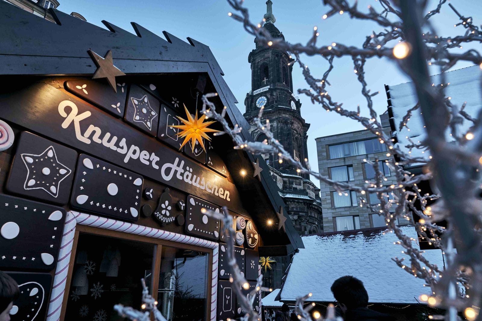 Weihnachtsmarkt in Dresden mit festlich beleuchtetem Knusperhaus und Kirchturm.