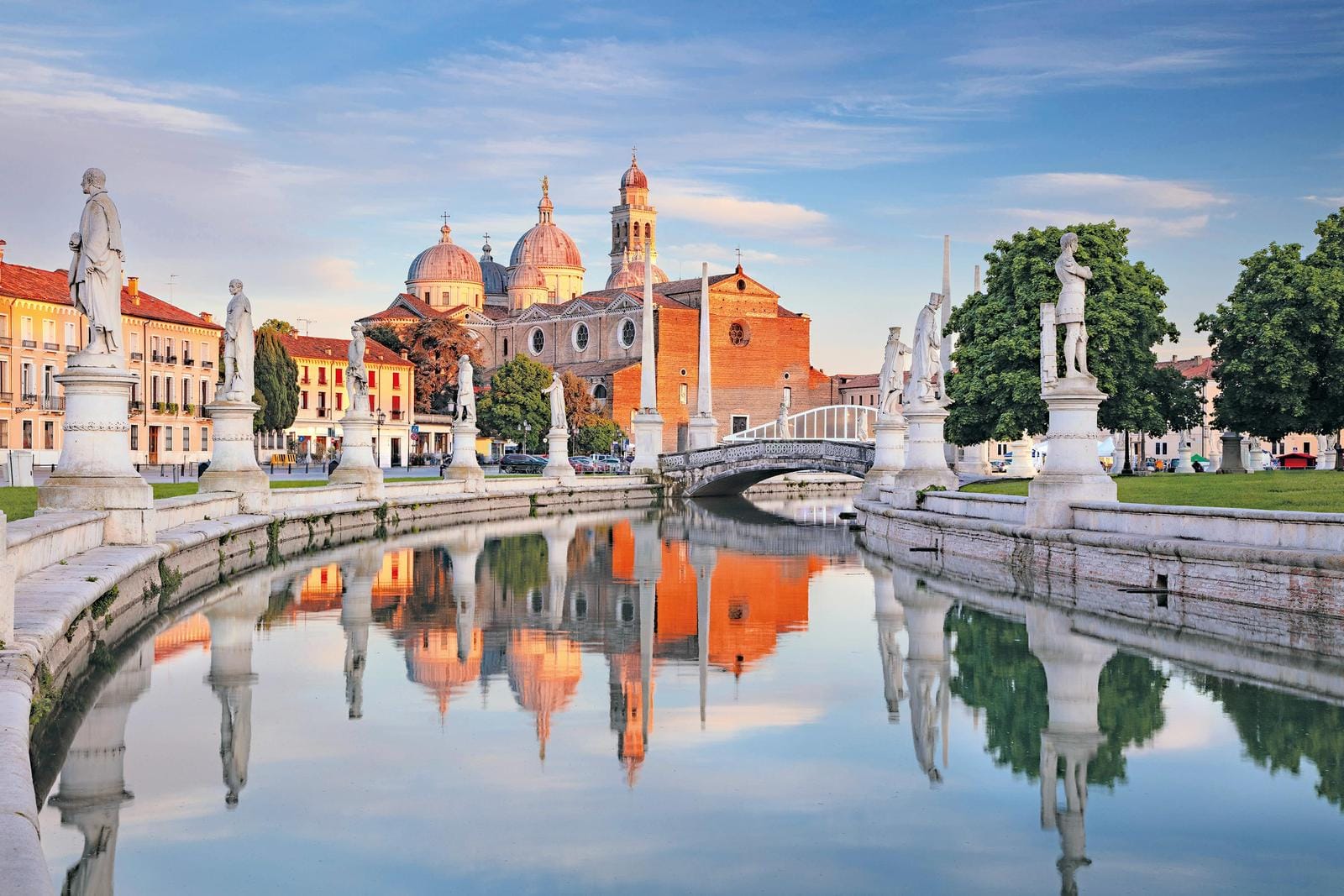 Zentraler Stadtkanal mit Statuen und Kirche in Padua, Italien, bei Sonnenuntergang.