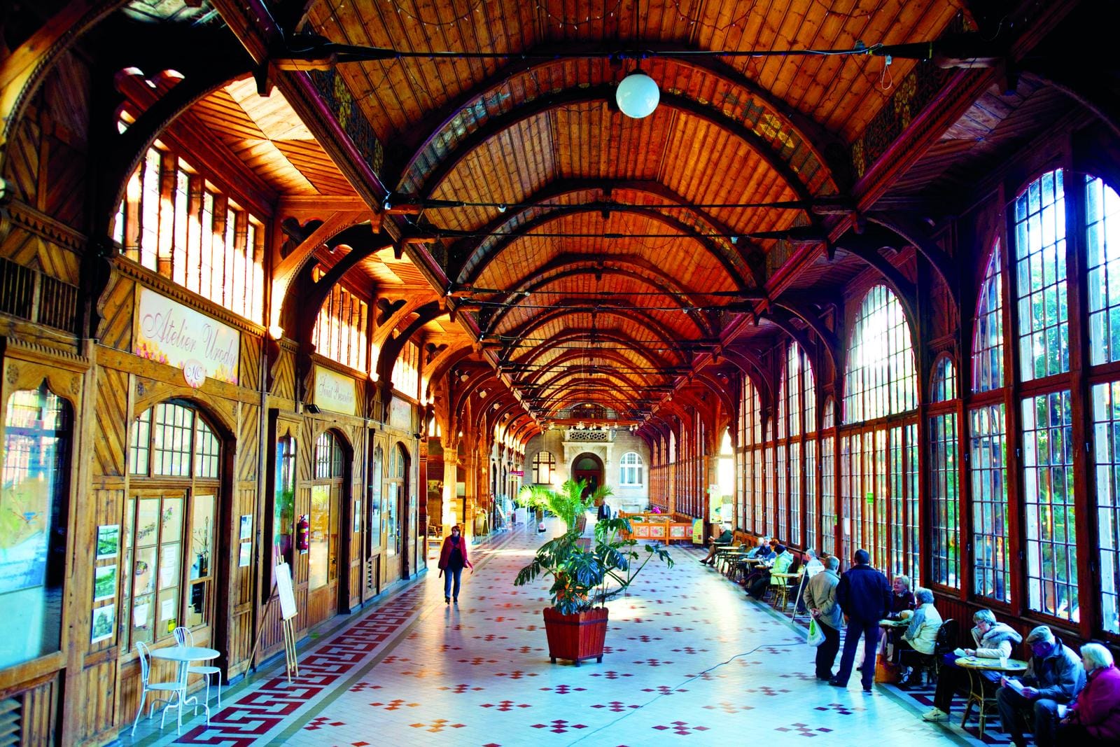 Historische Kolonnade mit Holzbögen und großen Fenstern in eleganter, heller Architektur.