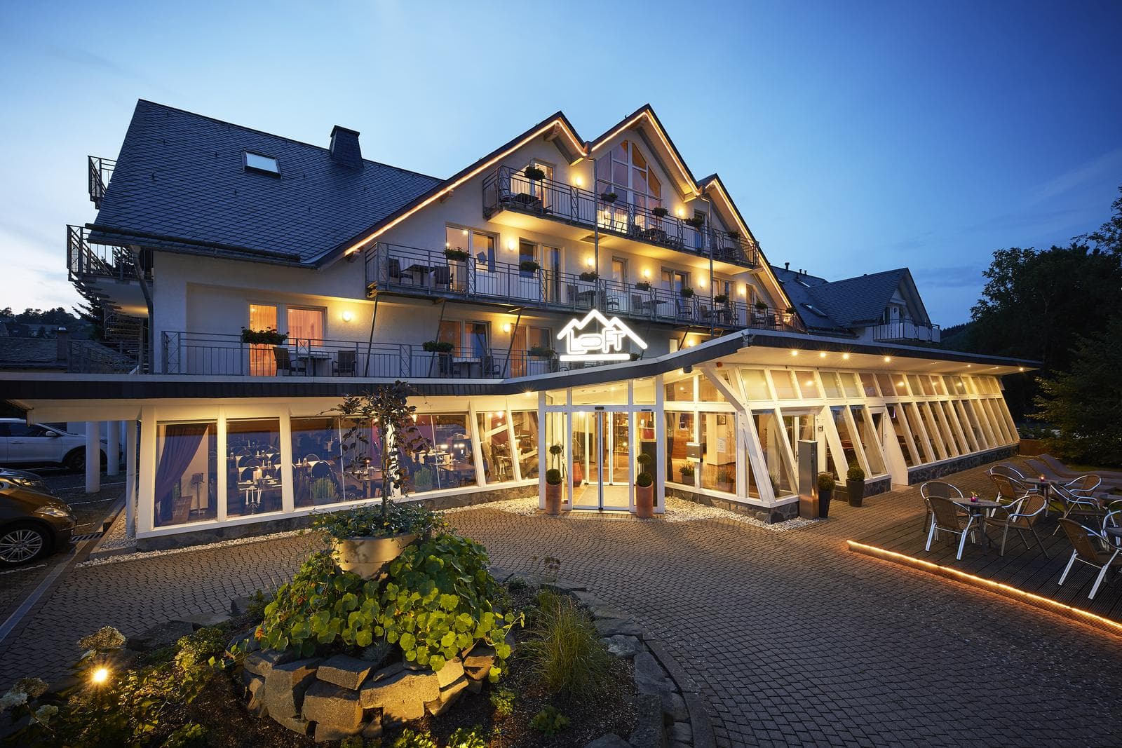 Gemütliches Hotel bei Dämmerung, stilvolle Beleuchtung und einladende, verglaste Lobby.