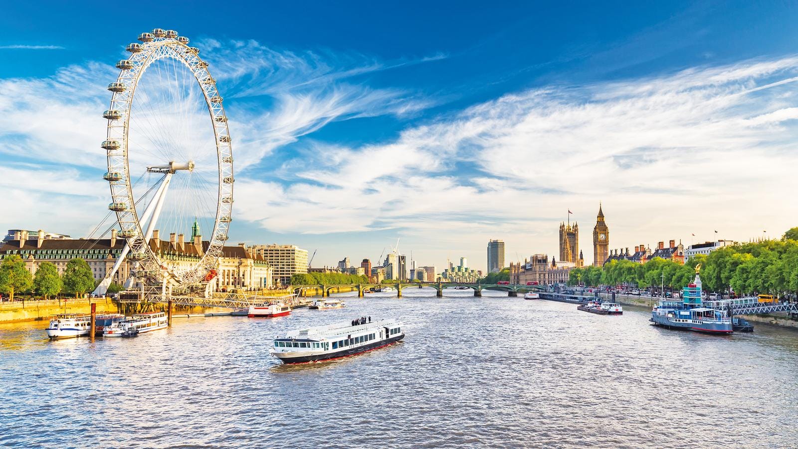 Das Bild zeigt das London Eye und die Themse im sonnigen London, voller Leben und Geschichte.