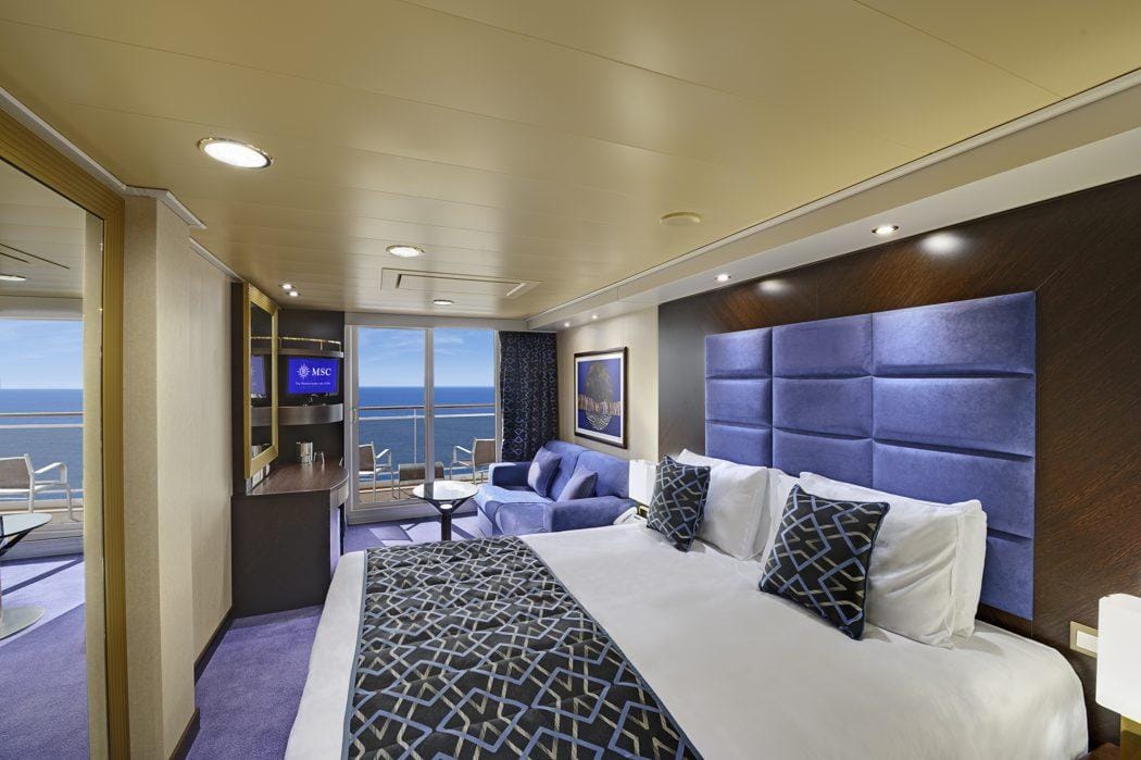 Luxuriöse Kabine mit Meerblick, blauem Kopfteil, modernem Dekor und Balkon.