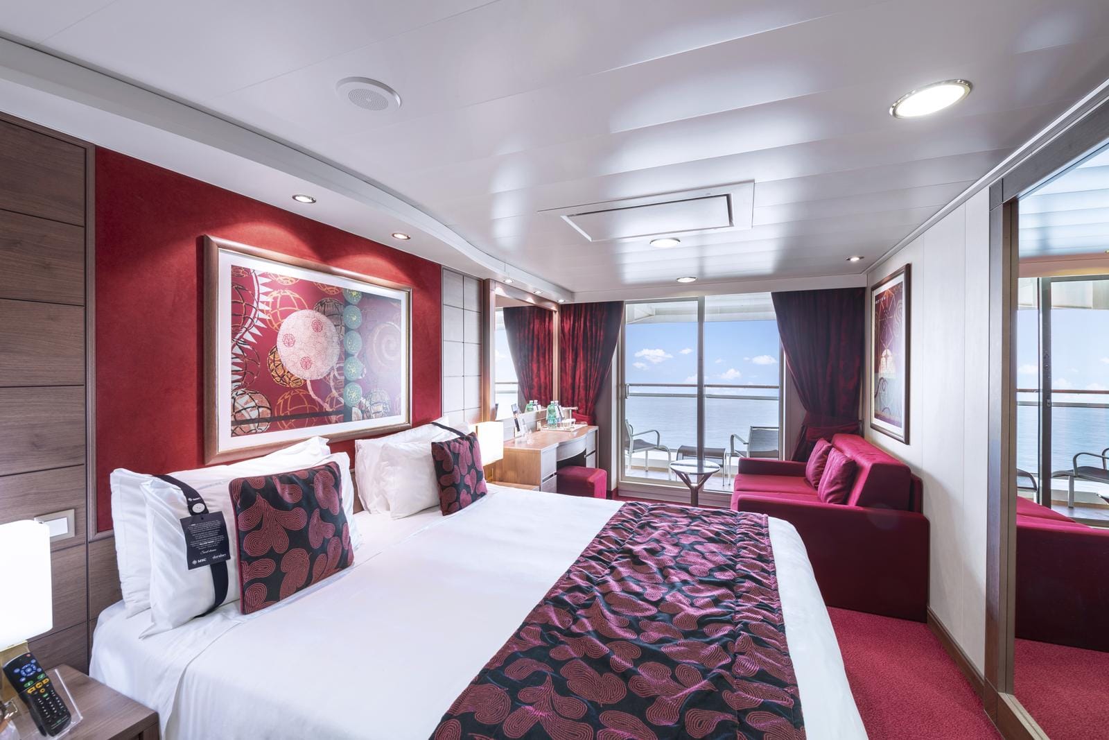 Elegantes Hotelzimmer mit Meerblick, roten Akzenten, Balkon und stilvollem Kunstwerk.