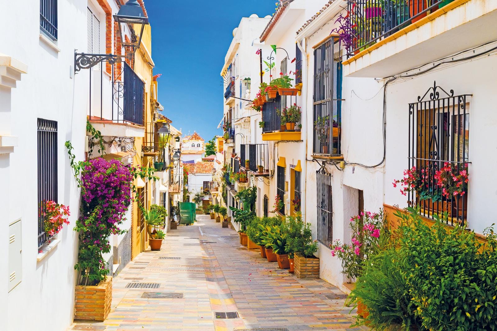 Bunte Altstadtgasse in Andalusien, Spanien mit Blumen und weiß getünchten Häuschen.