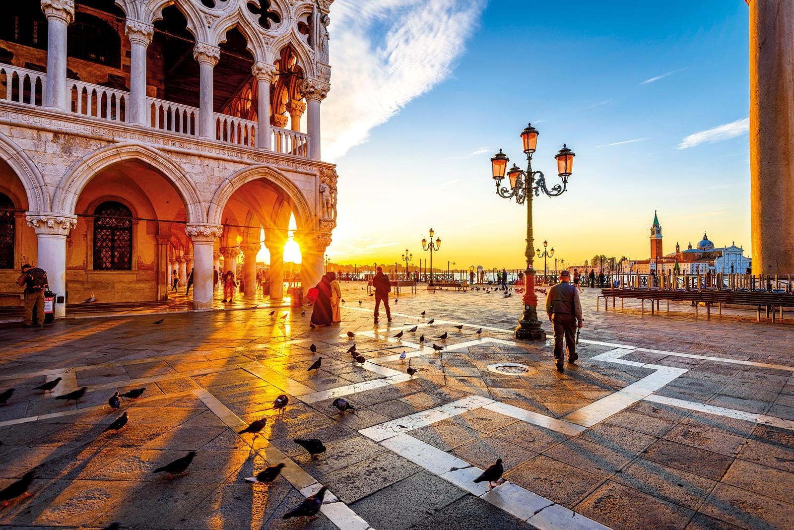 Sonnenuntergang auf dem Markusplatz in Venedig, Italien, mit Tauben und historischen Gebäuden.