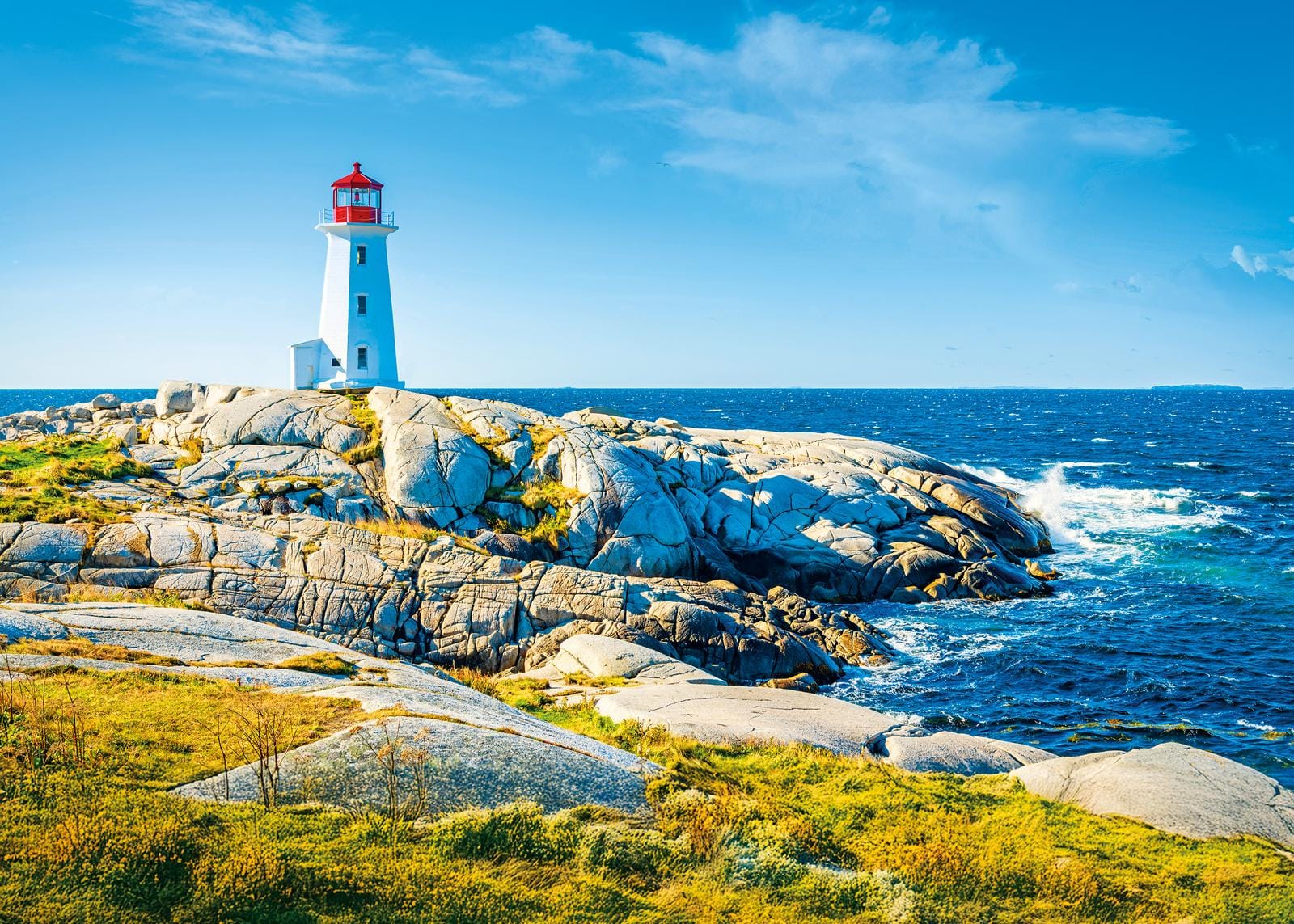 Ein Leuchtturm auf felsiger Küste in Nova Scotia, Kanada, mit blauem Himmel und Meer.
