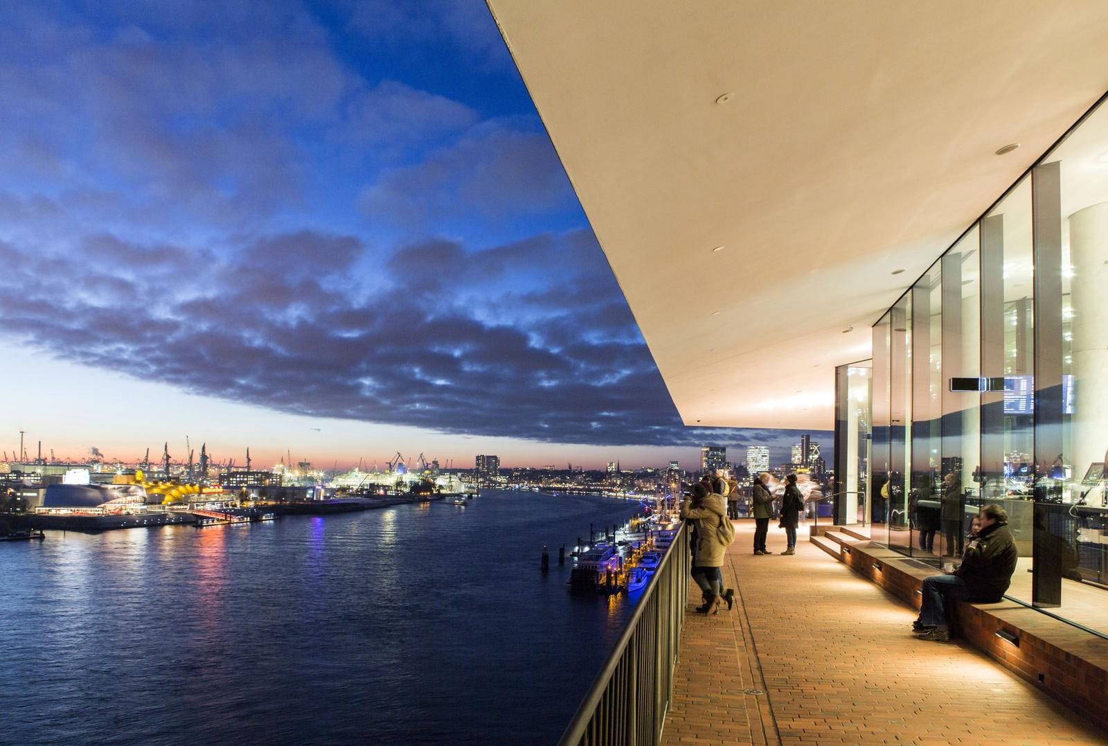 Abendlicher Blick von der Elbphilharmonie in Hamburg über den beleuchteten Hafen.