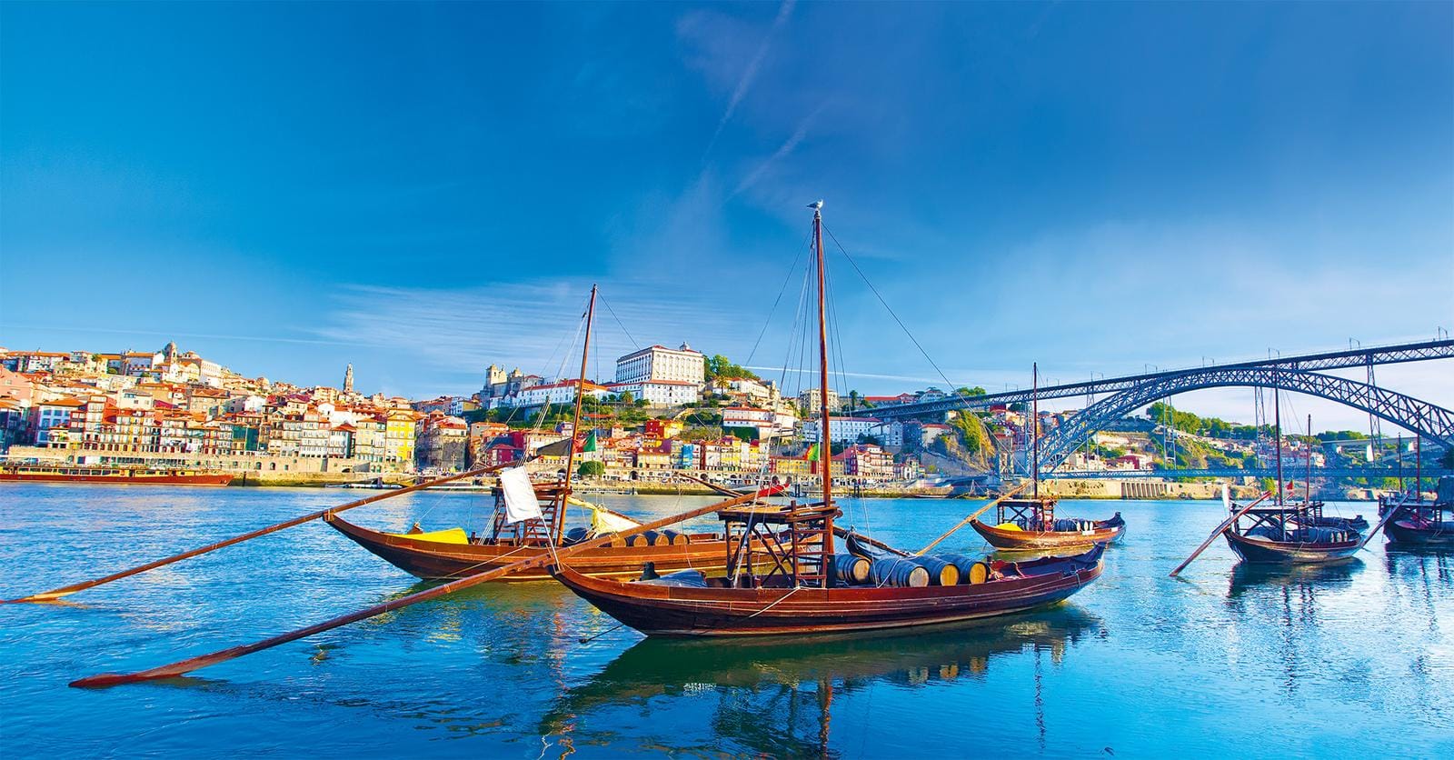 Boote auf dem Douro vor farbenfroher Altstadt und Brücke in Porto, Portugal.