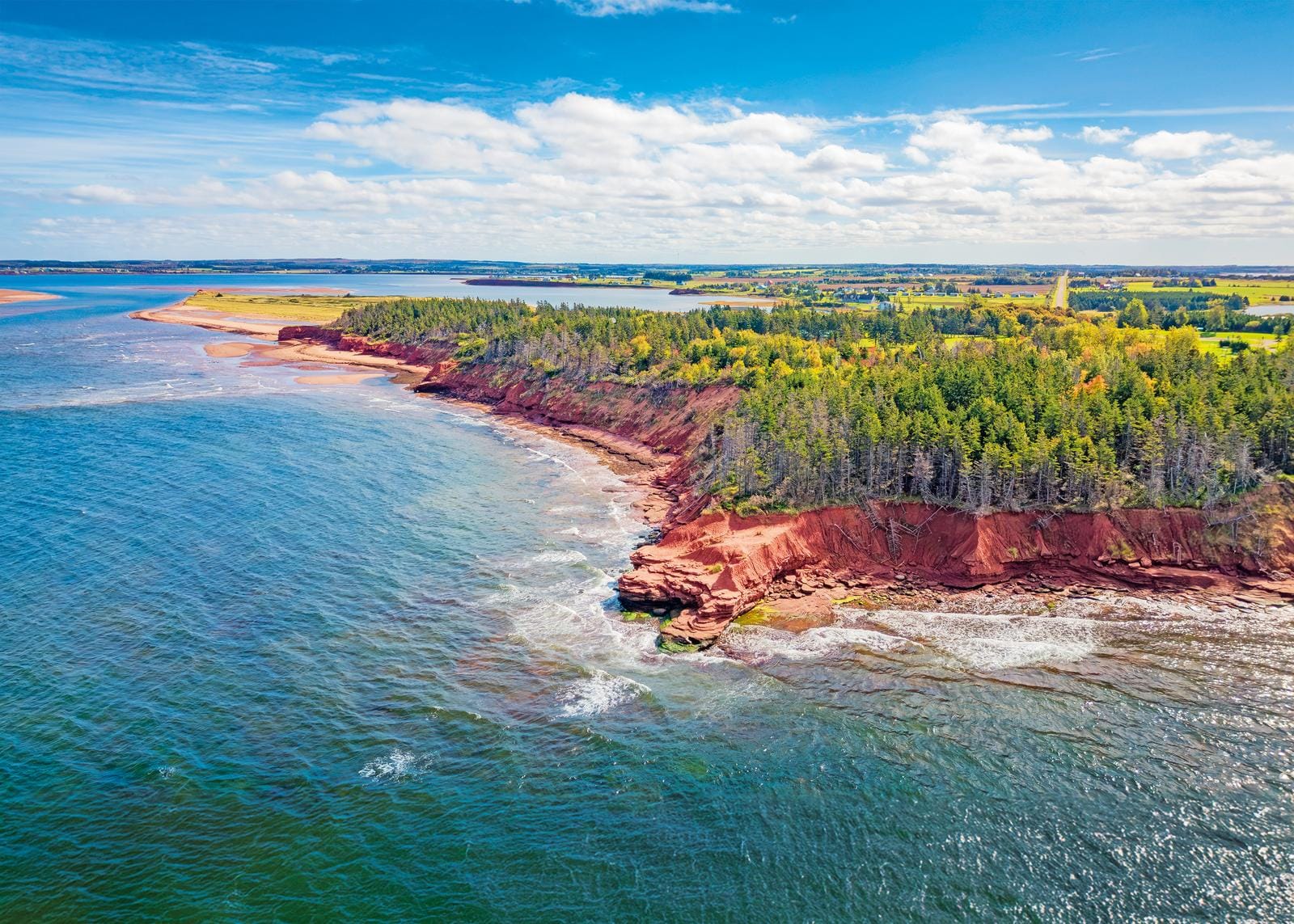 Klippen und Wälder an der Küste von Prince Edward Island, Kanada, unter blauem Himmel.