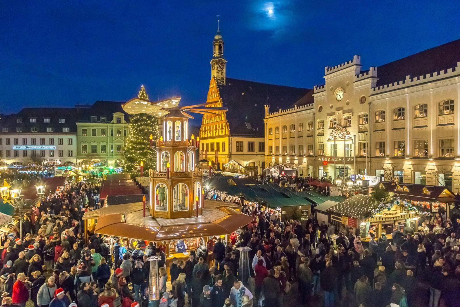 Weihnachtsmarkt bei Nacht in Deutschland mit Lichtern, Menschenmengen und Fachwerkhäusern.
