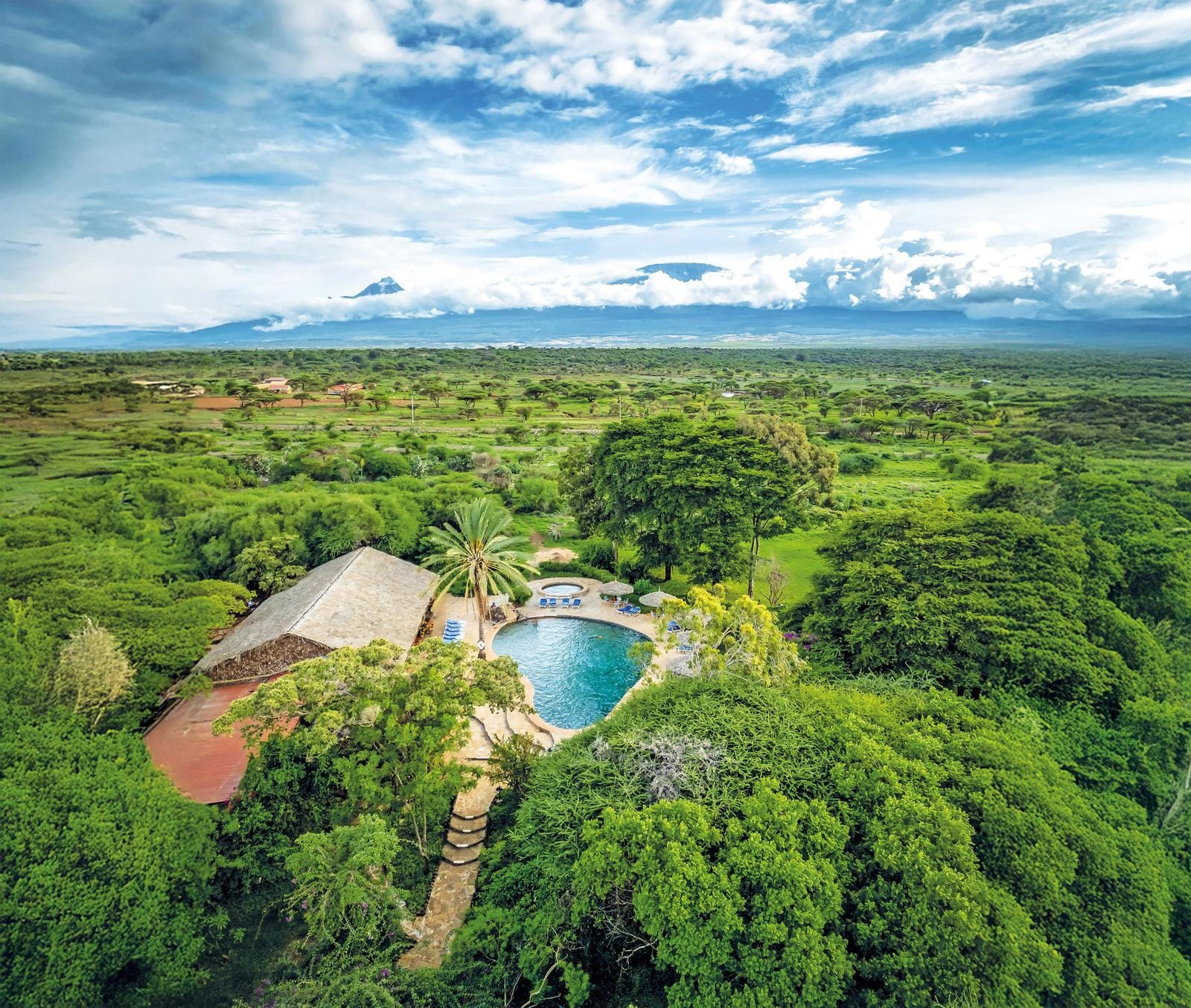 Grünes Paradies mit Pool in Kenia, umgeben von üppiger Natur und majestätischem Bergblick.