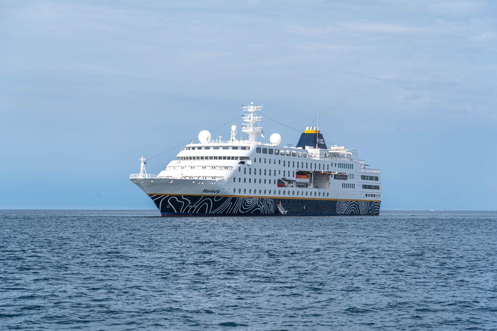 Kreuzfahrtschiff auf ruhiger See, modernes Design, weiĂźe Farbe mit blauen Akzenten.