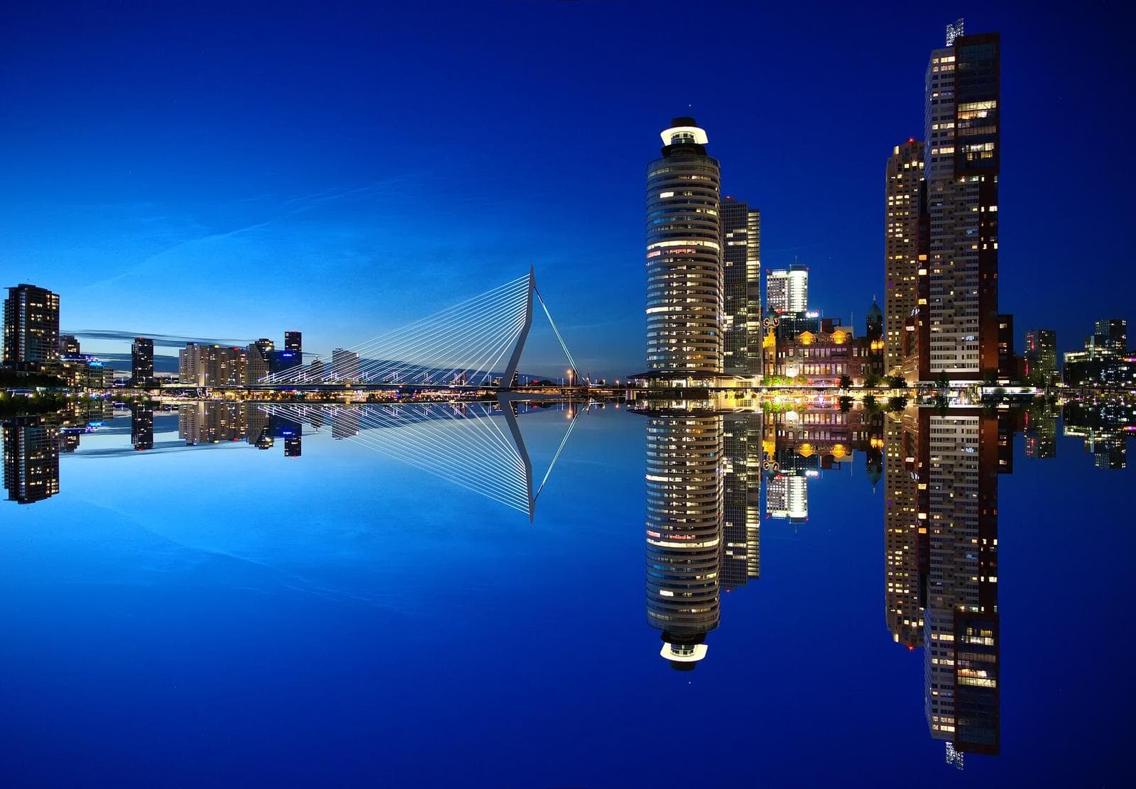 Moderne Skyline bei Nacht spiegelt sich im Wasser, beeindruckend in Rotterdam, Niederlande.