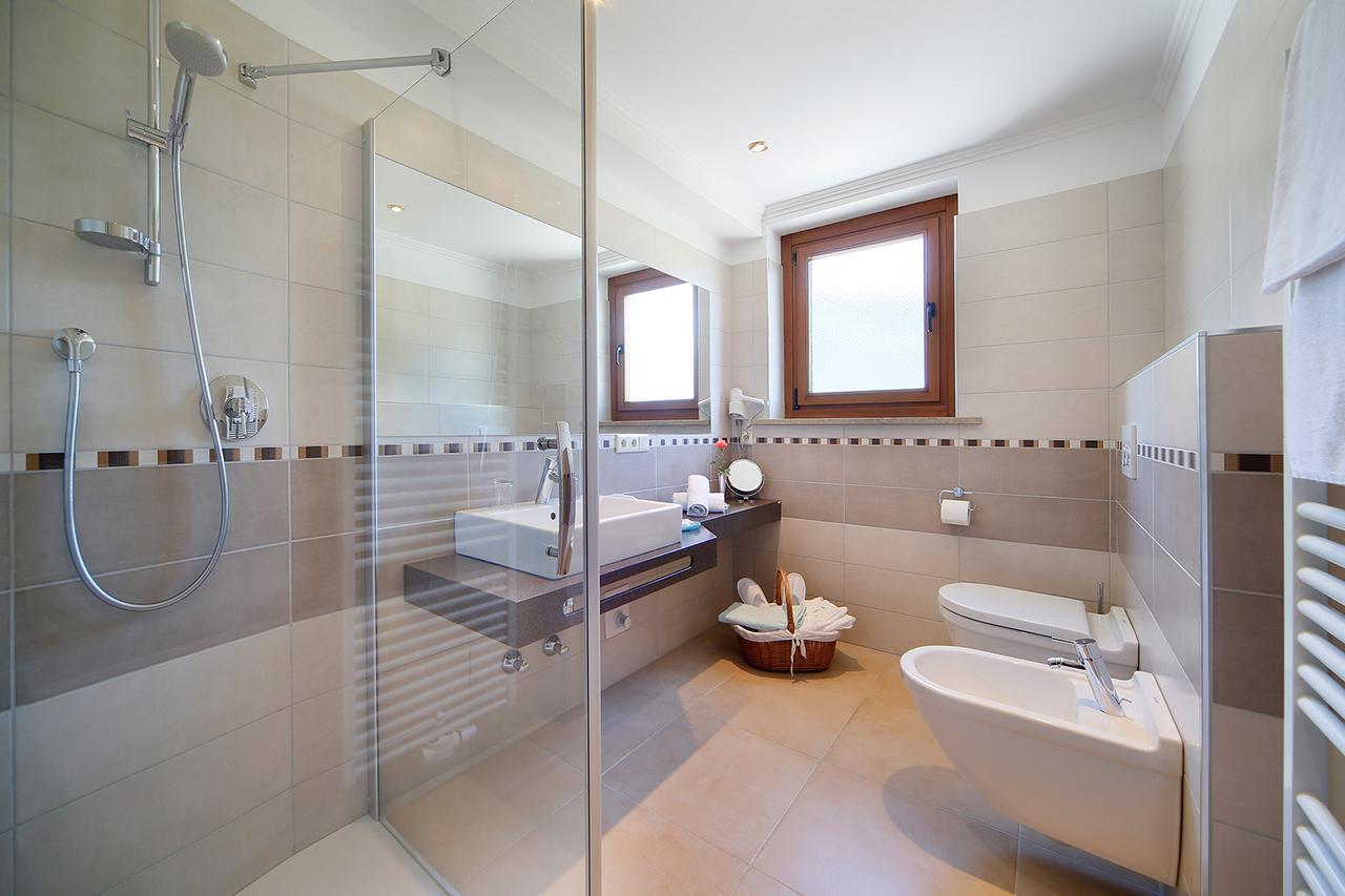 Modernes Badezimmer in neutralen Tönen mit Glasdusche und großen Fenstern.