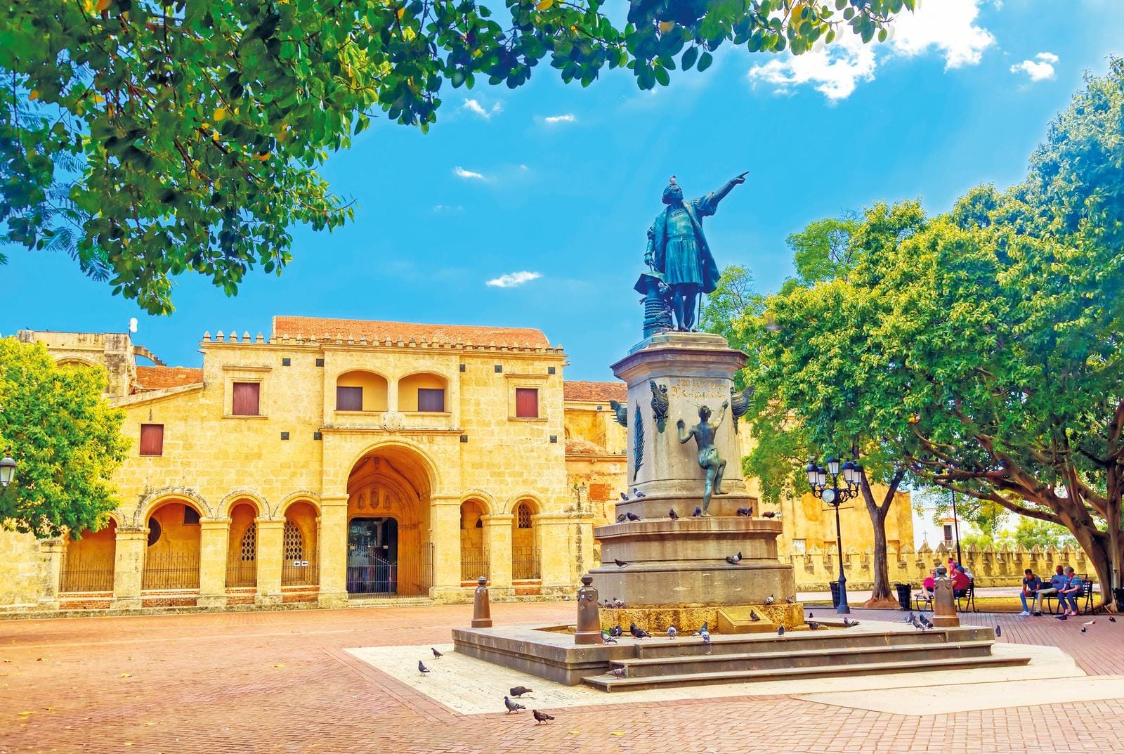 Koloniales Gebäude und Statue in sonnigem Park in Santo Domingo, Dominikanische Republik.