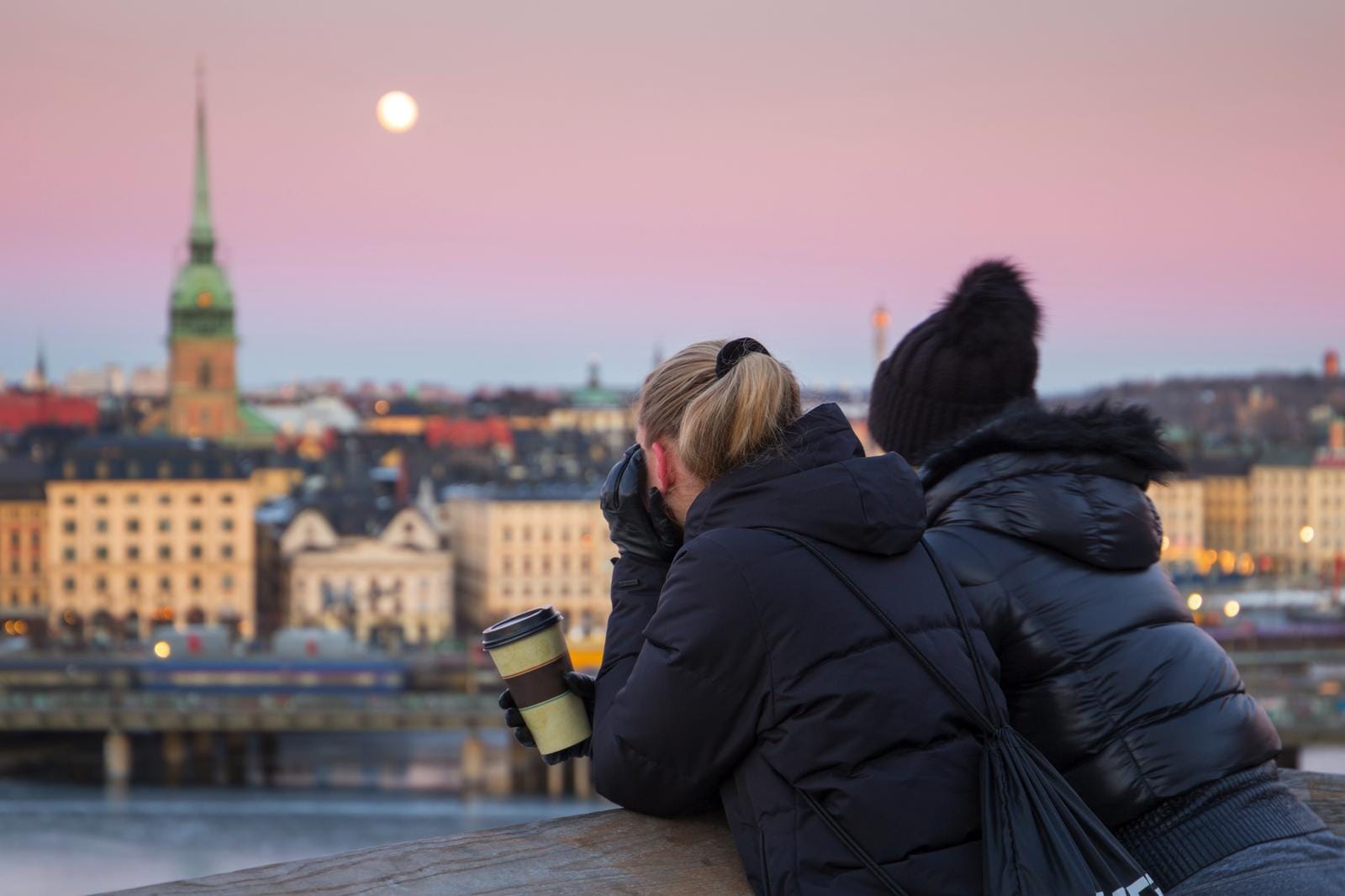 Zwei Personen betrachten bei Sonnenuntergang die malerische Skyline von Stockholm, Schweden.