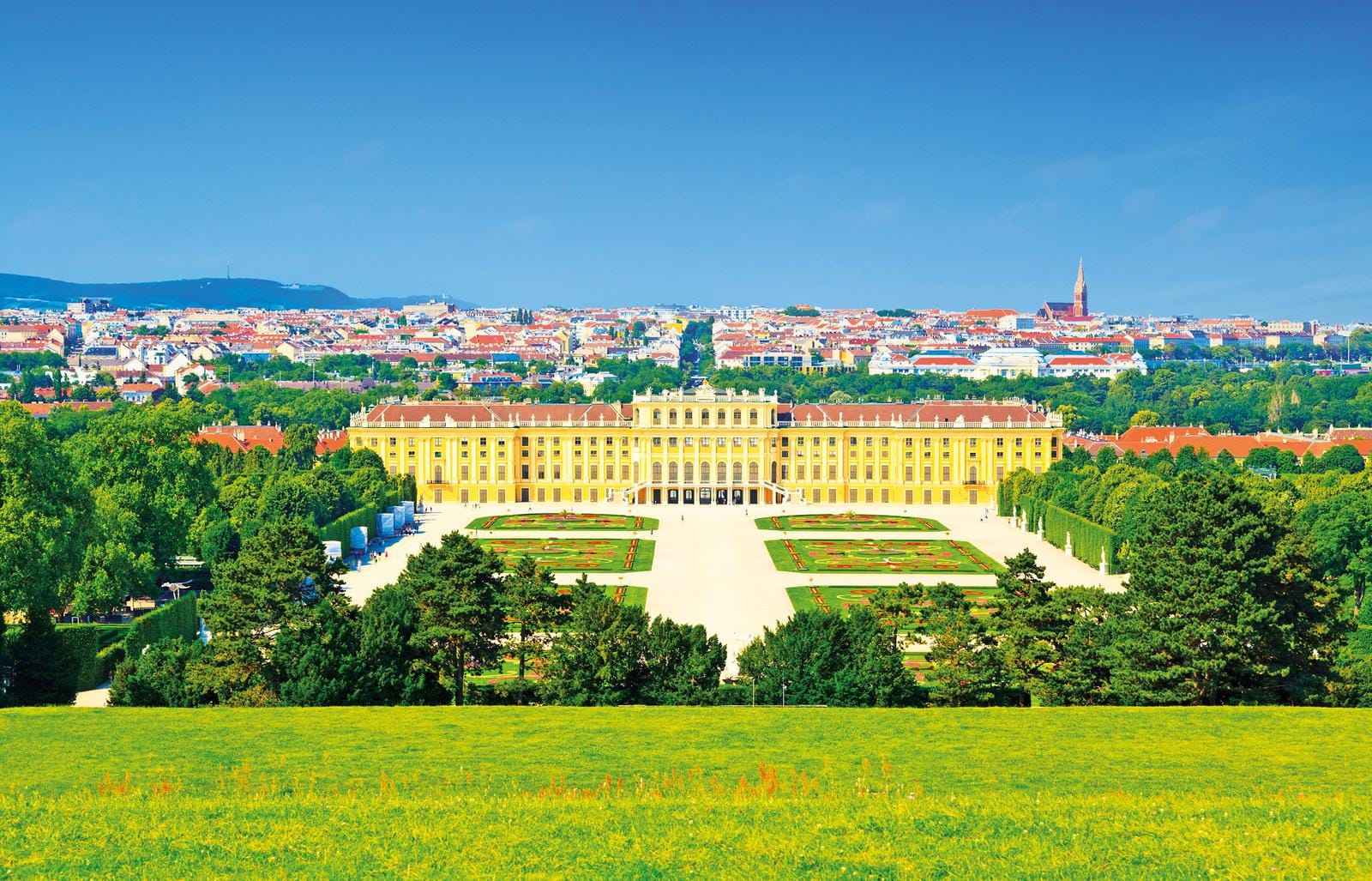 Prächtiges Schloss mit weitläufigem Garten in Wien, umgeben von grüner Natur und Stadtblick.