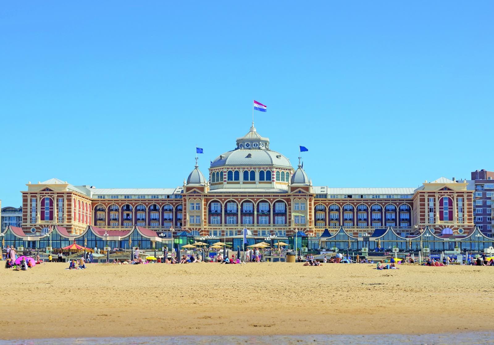 Historisches Gebäude am Strand von Scheveningen, Niederlande, unter klarem, blauen Himmel.