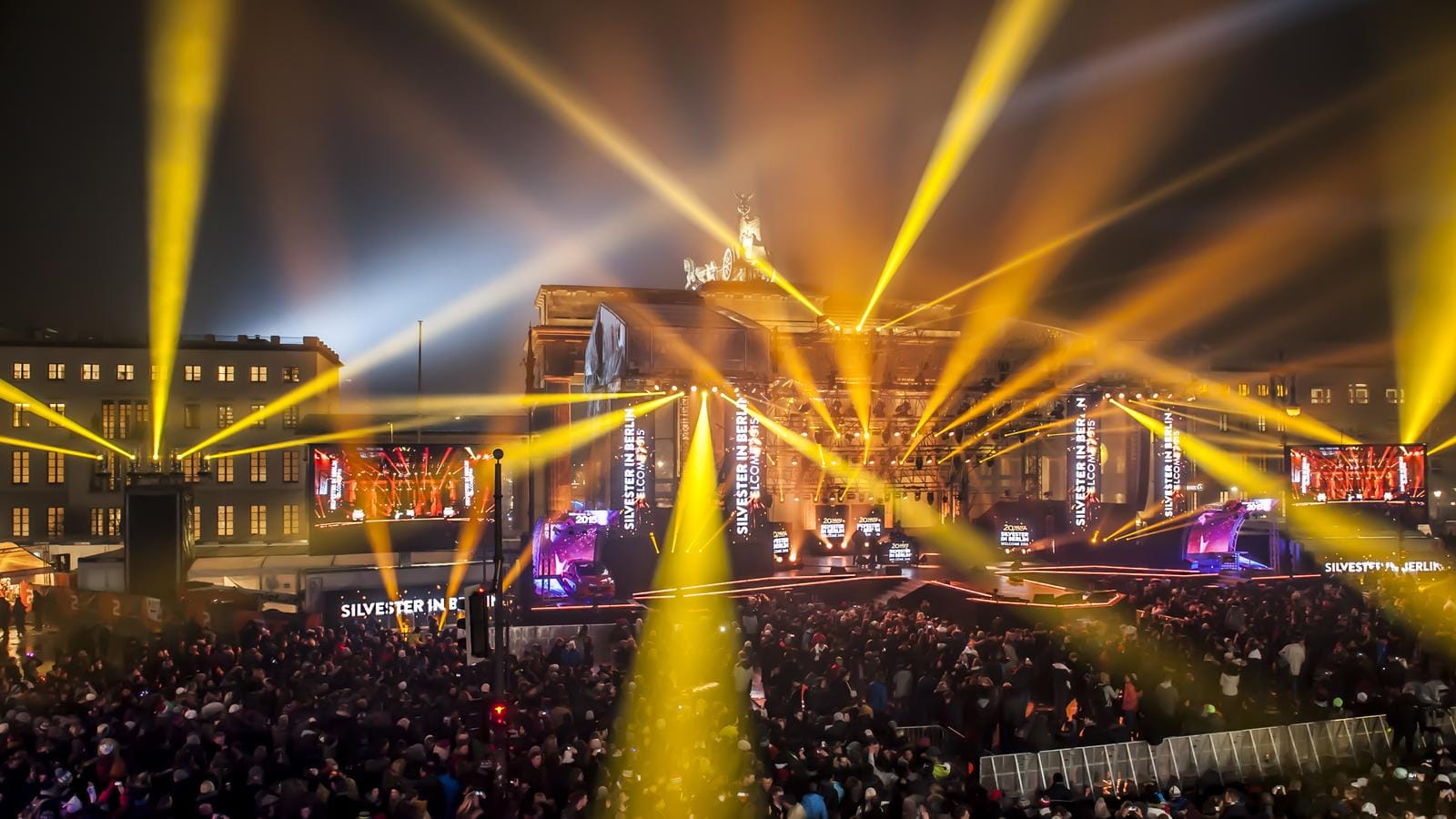 Silvesterfeier am Brandenburger Tor in Berlin mit goldenen Lichtern und Menschenmenge.