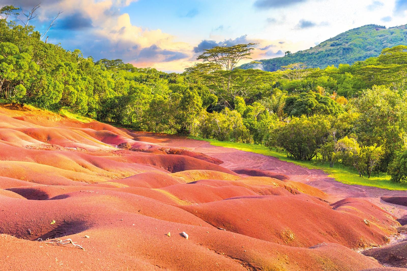 Bunte Sanddünen bei Sonnenuntergang, umgeben von üppigem Grün, Mauritius.