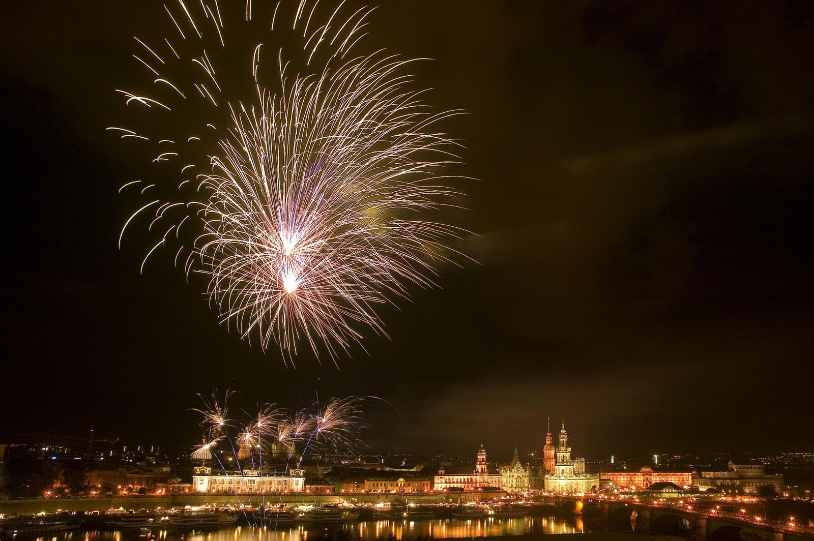 Feuerwerk über Dresden: Lichter erleuchten die nächtliche Skyline und spiegeln sich in der Elbe.