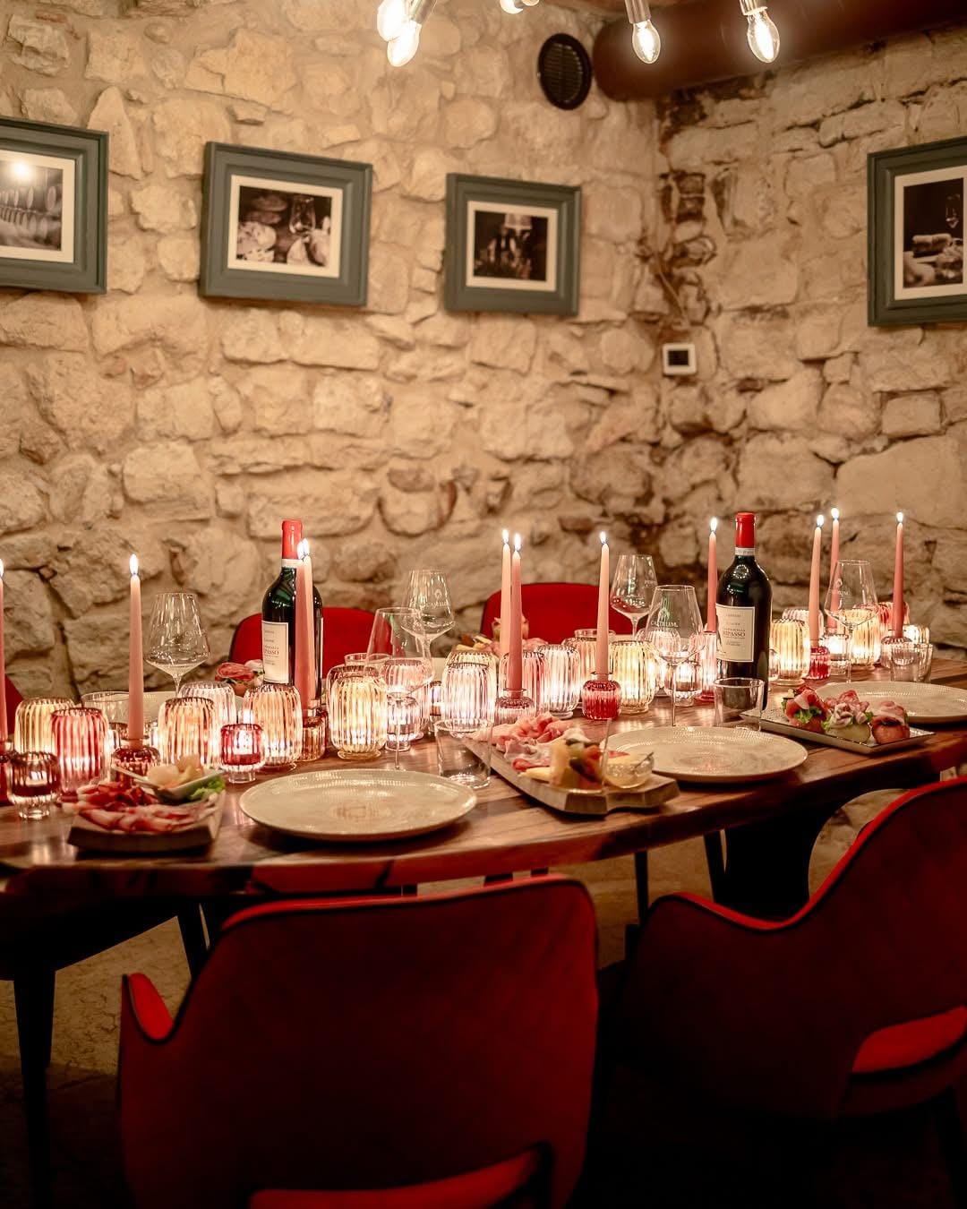 Gemütlicher Speiseraum mit Steinwand, rotem Stuhl, Kerzenlicht und gedecktem Tisch.