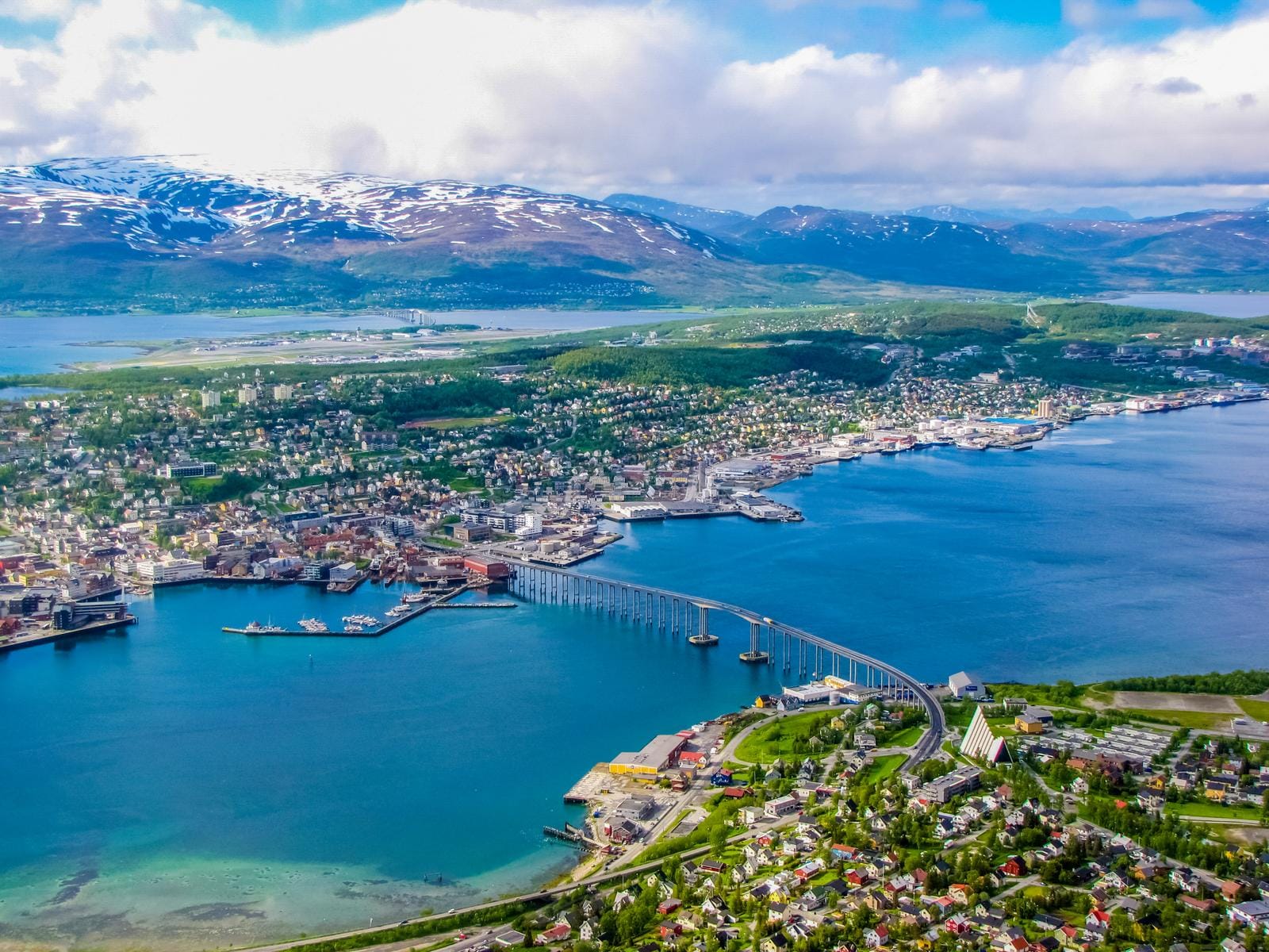 Küstenstadt Tromsø, Norwegen, mit Brücke, Bergen und blauem Wasser im Frühling.
