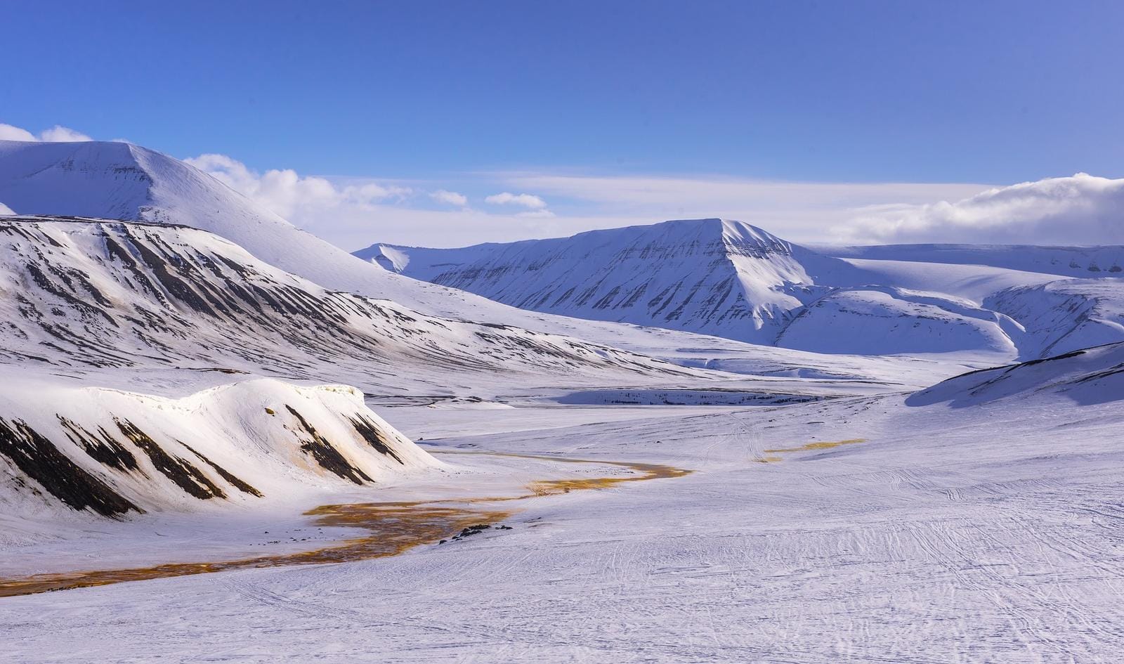 Schneebedeckte Berglandschaft auf Spitzbergen unter blauem Himmel.