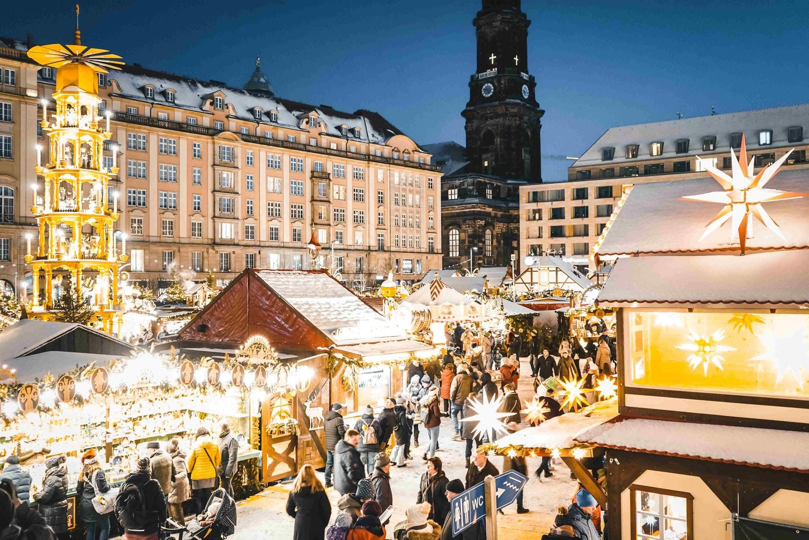 Weihnachtsmarkt in Dresden, Deutschland, beleuchtet mit Sternen und Menschen bei Nacht.