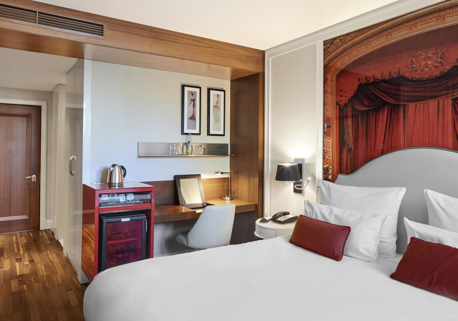 Modernes Hotelzimmer mit Wandkunst, Holzdetails und Schreibtisch, warmes Ambiente.