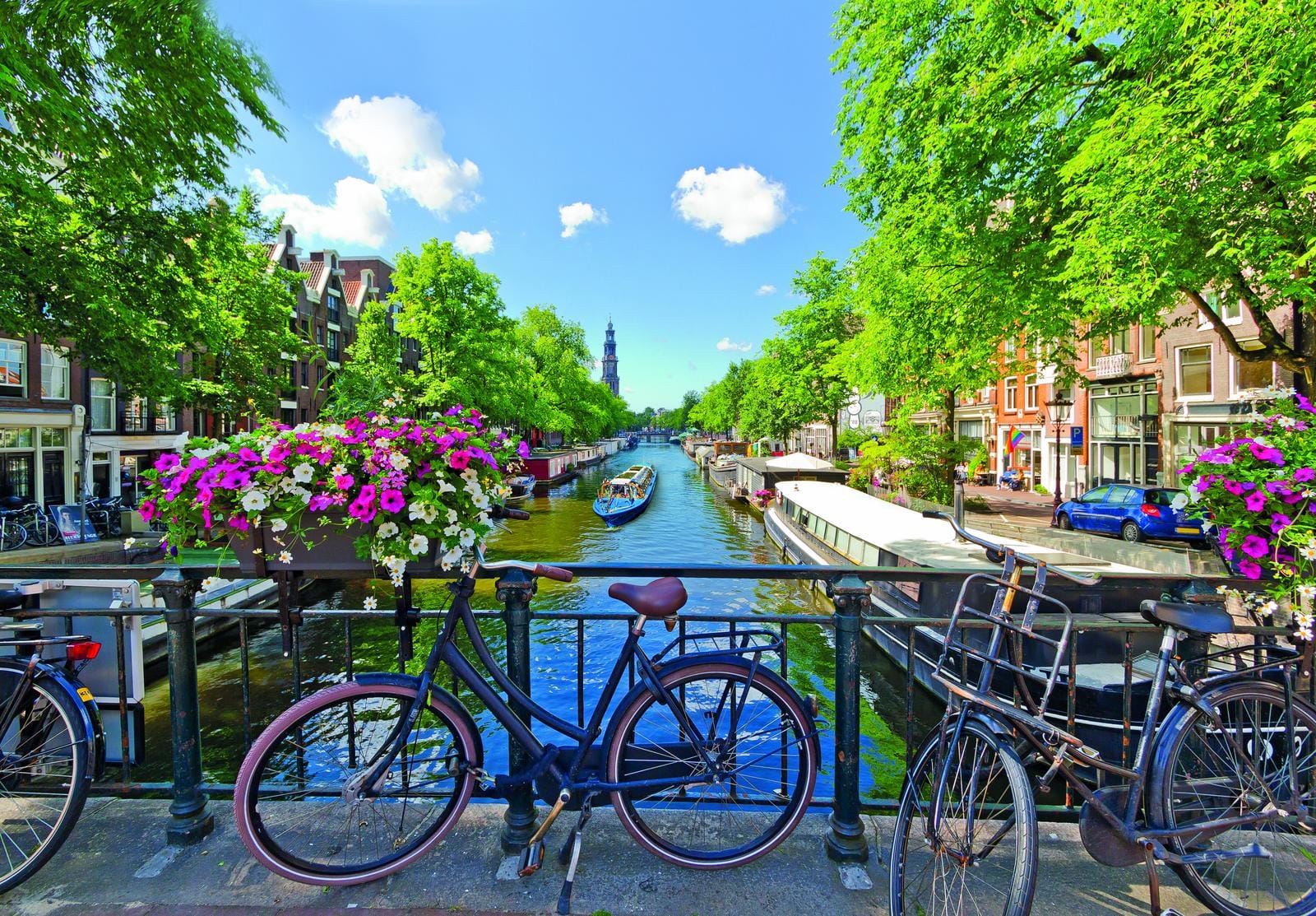 Amsterdam, Niederlande; Kanalblick mit Fahrrädern, blühenden Pflanzen, blauem Himmel.