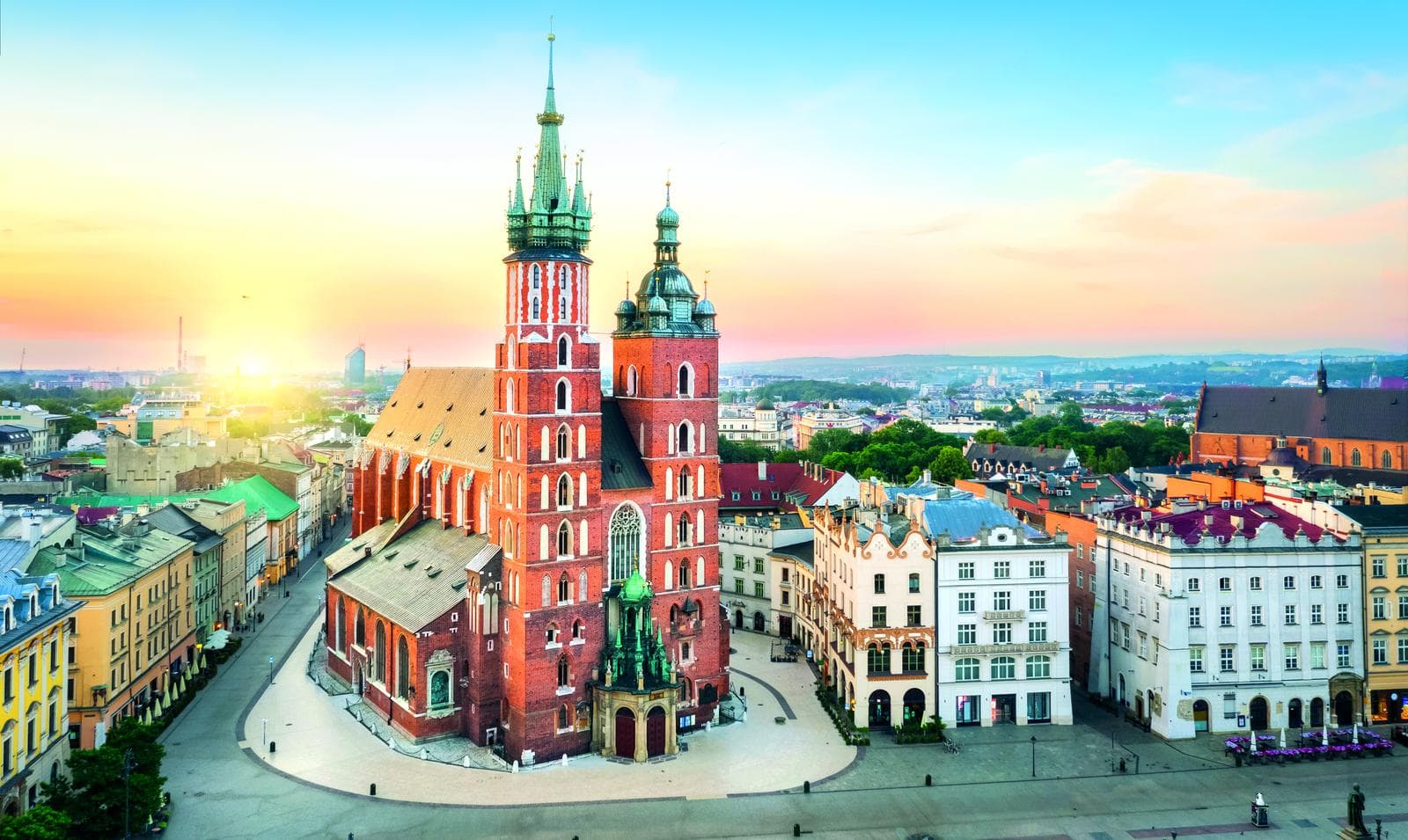 Marktplatz mit Marienkirche in Krakau, Polen, bei Sonnenuntergang, helle Farben, ruhige Atmosphäre.